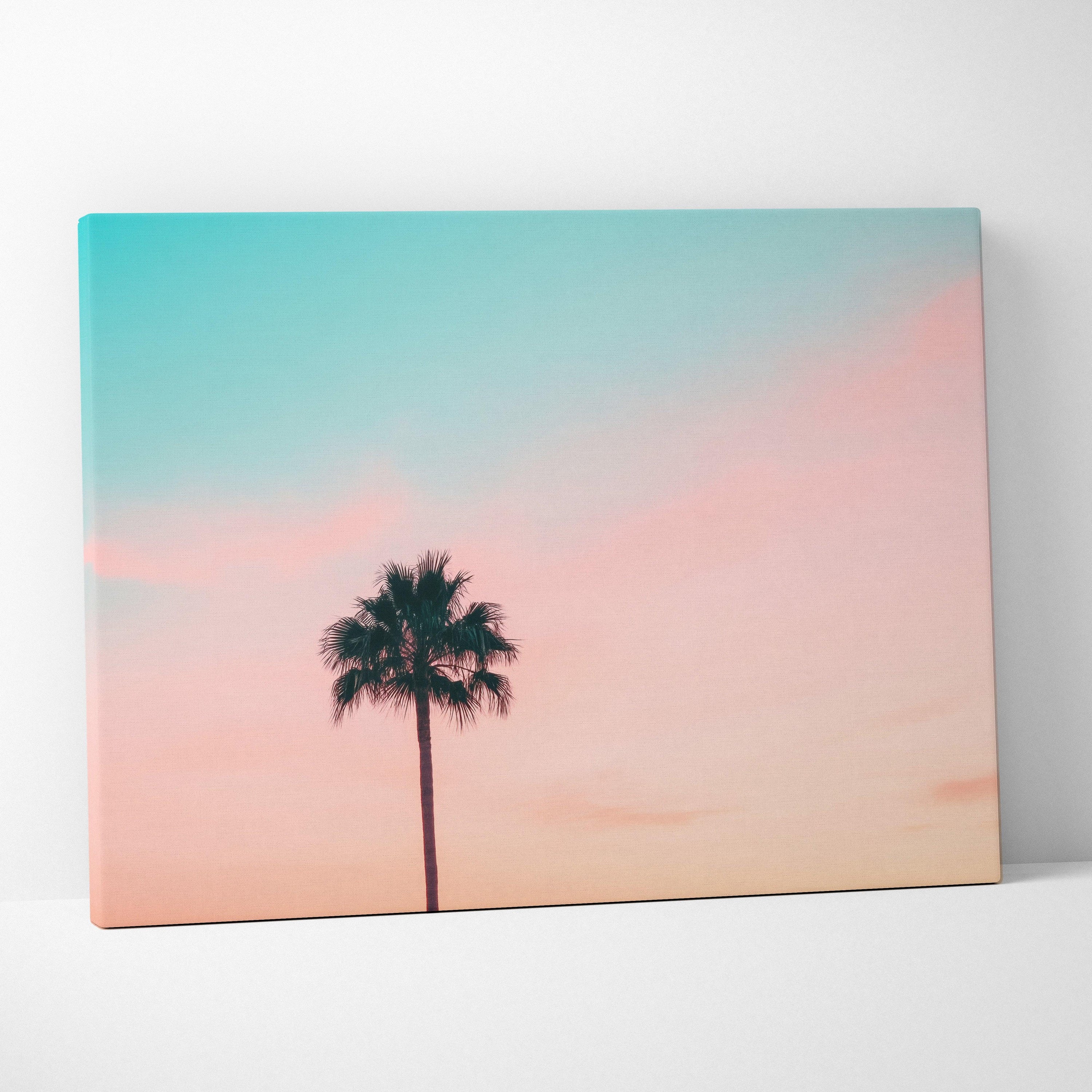Minimalist canvas wall art of palm tree silhouette against pastel blue and pink sunset sky decor.