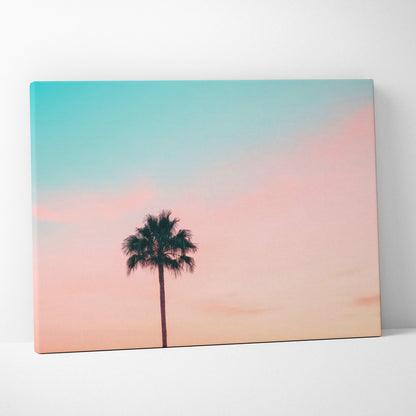 Minimalist canvas wall art of palm tree silhouette against pastel blue and pink sunset sky decor.