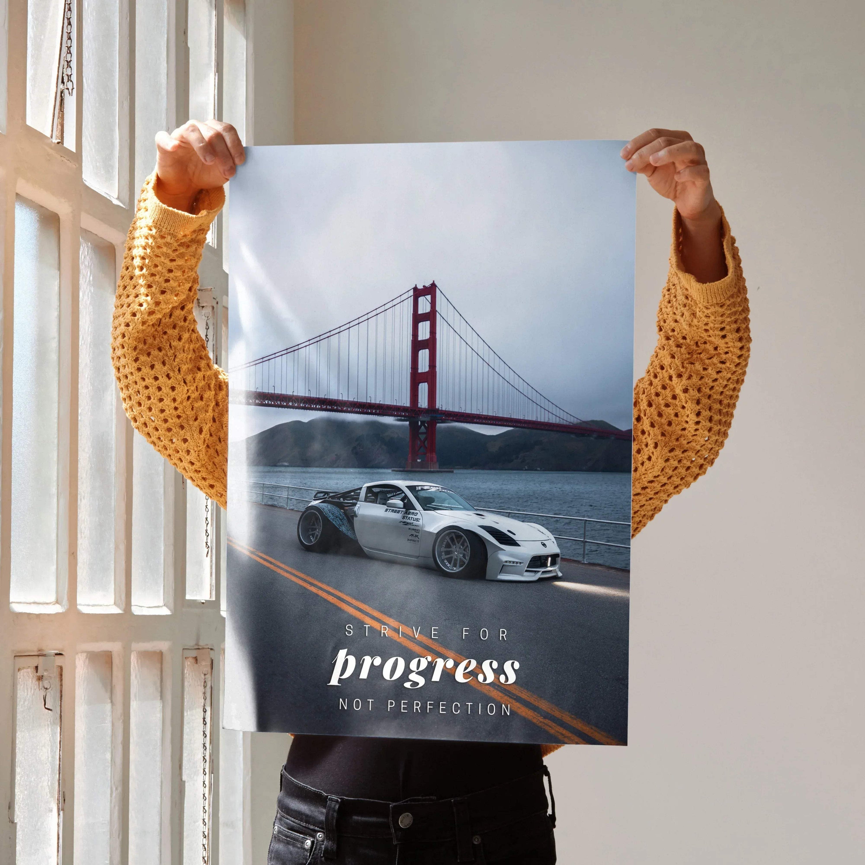 Motivational Nissan 350z poster wall art featuring a silver car by the Golden Gate Bridge with inspiring text progress not.