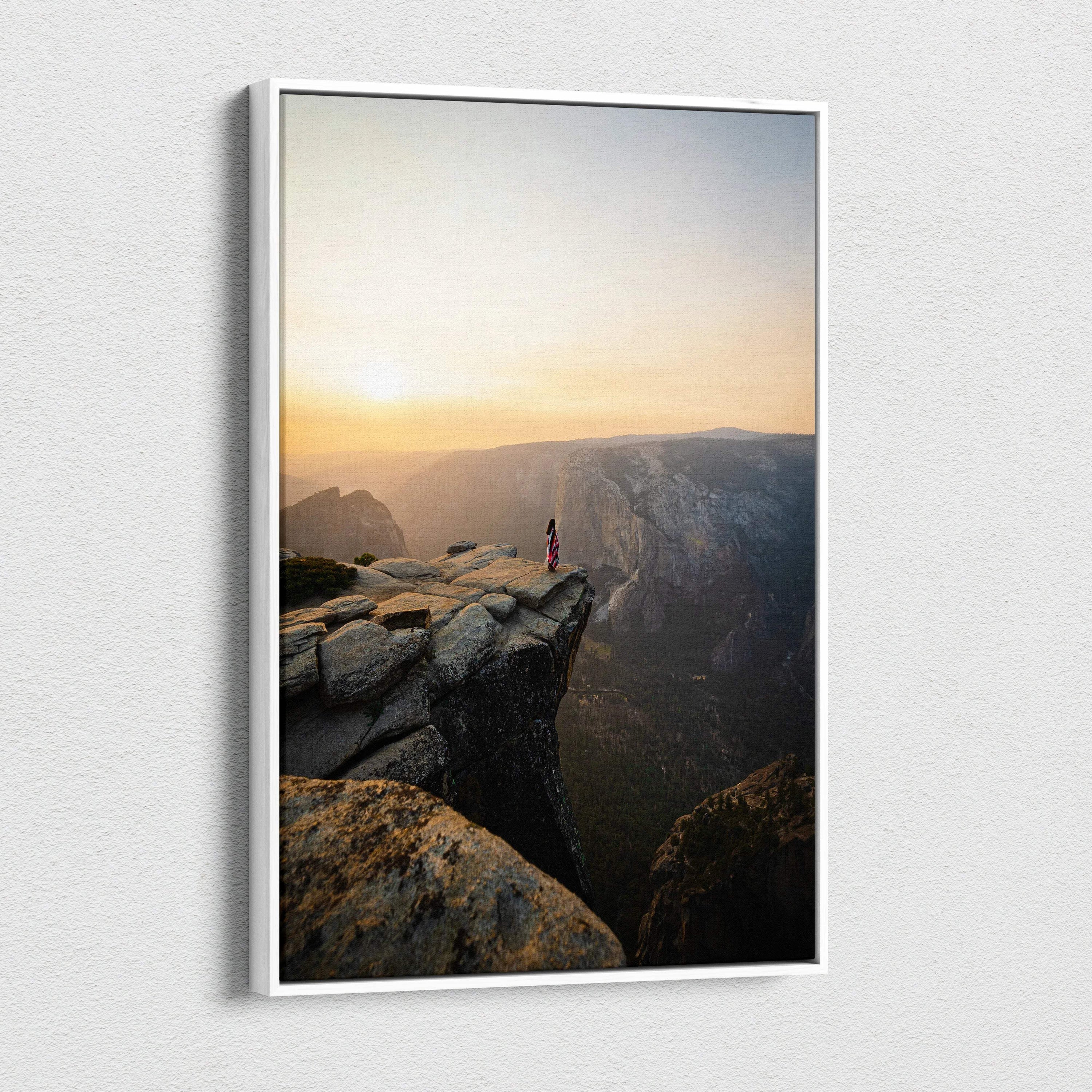 White-framed canvas print of solitary red figure on granite cliff at sunrise canyon