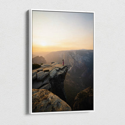 White-framed canvas print of solitary red figure on granite cliff at sunrise canyon