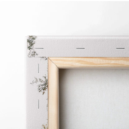 Close-up of wooden frame and stapled edge on white canvas wall art with slight botanical print on corner.