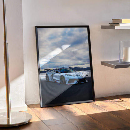 Chevrolet C8 Corvette poster wall art print with showroom white sports car and cloudy sky background in black frame on wood.