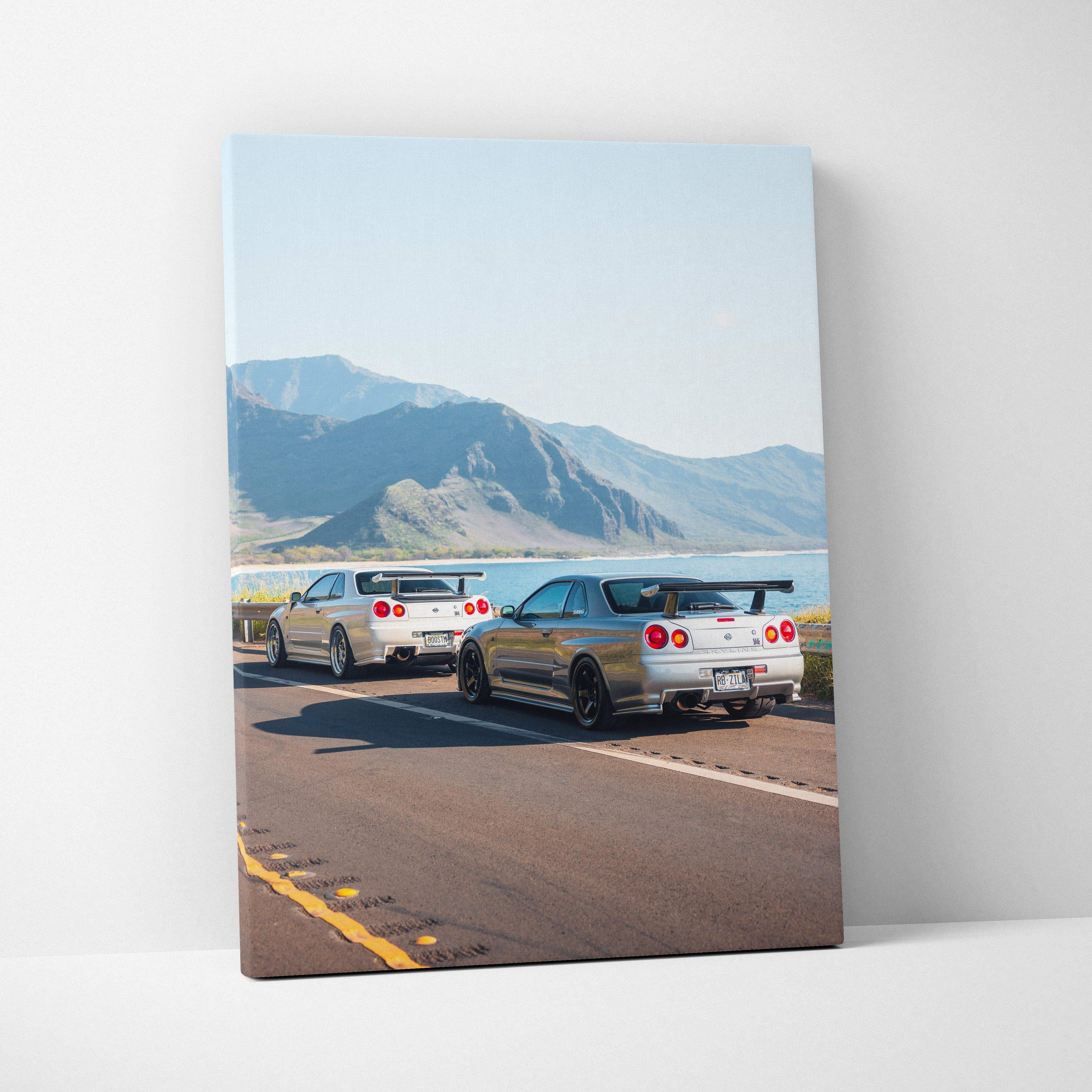Nissan GTR R34 Skyline cars driving on open road canvas wall art with mountain background.