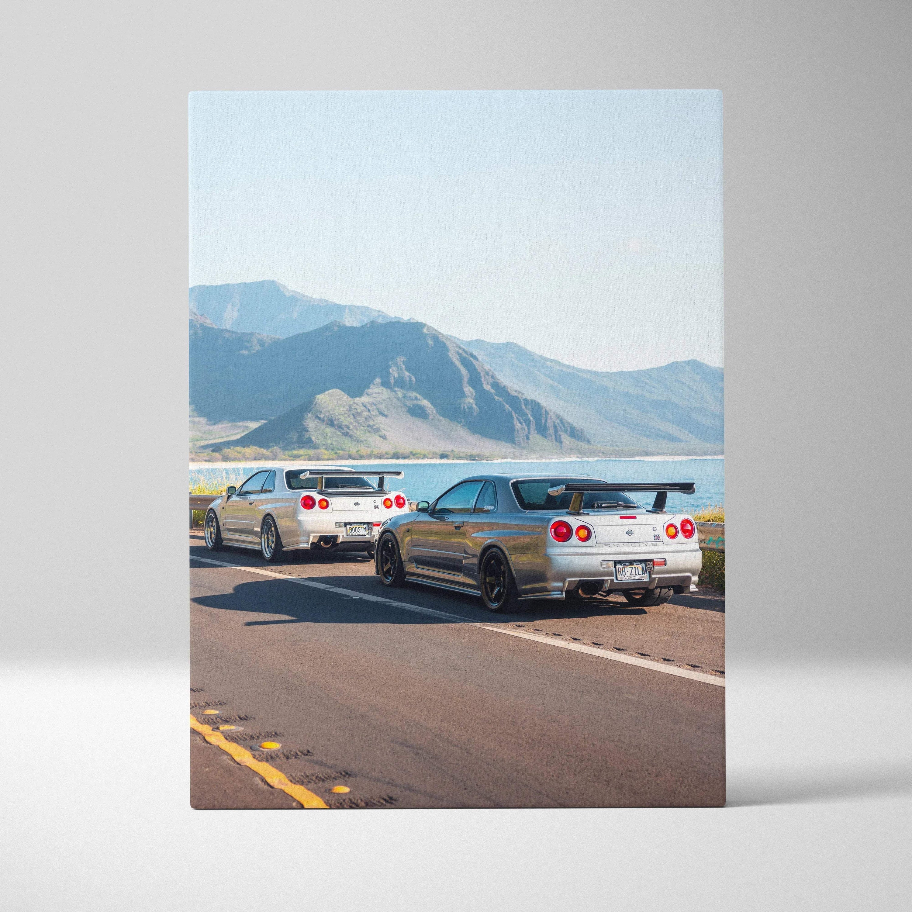 Vertical canvas art featuring two Nissan GTR R34 Skylines on an open road with mountains in the background.