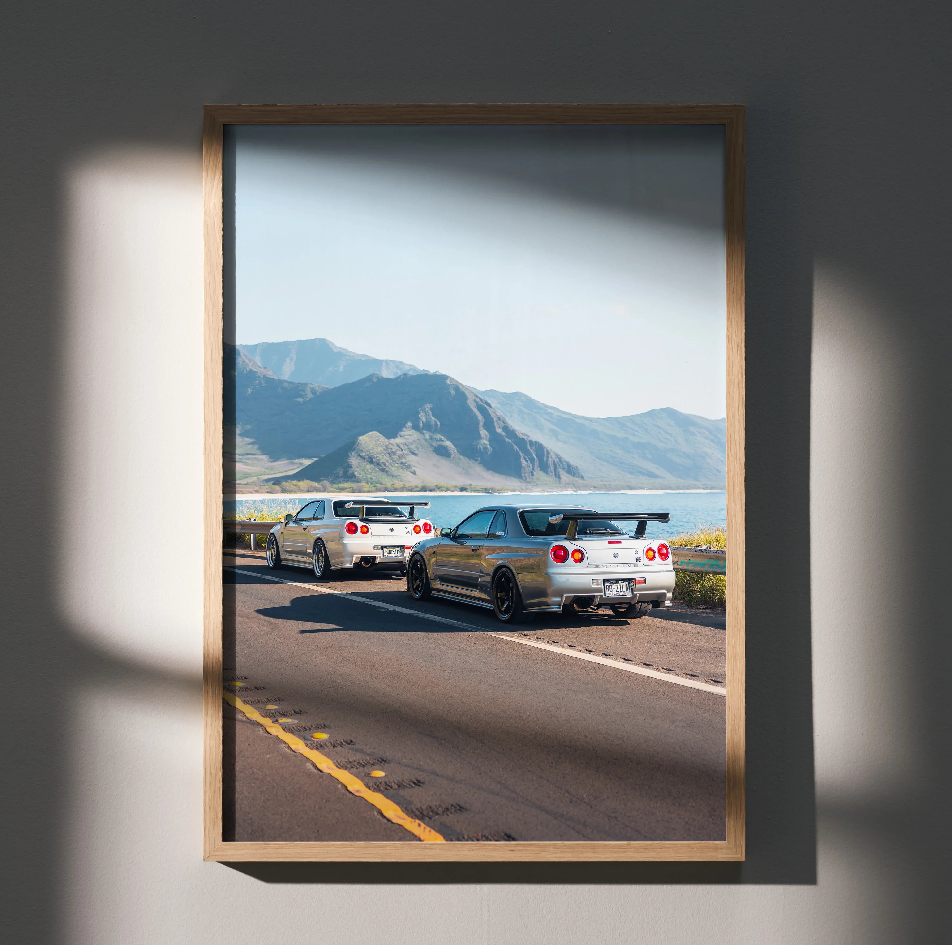 Nissan GT-R R34 Skyline cars driving on highway poster wall art with mountain background.