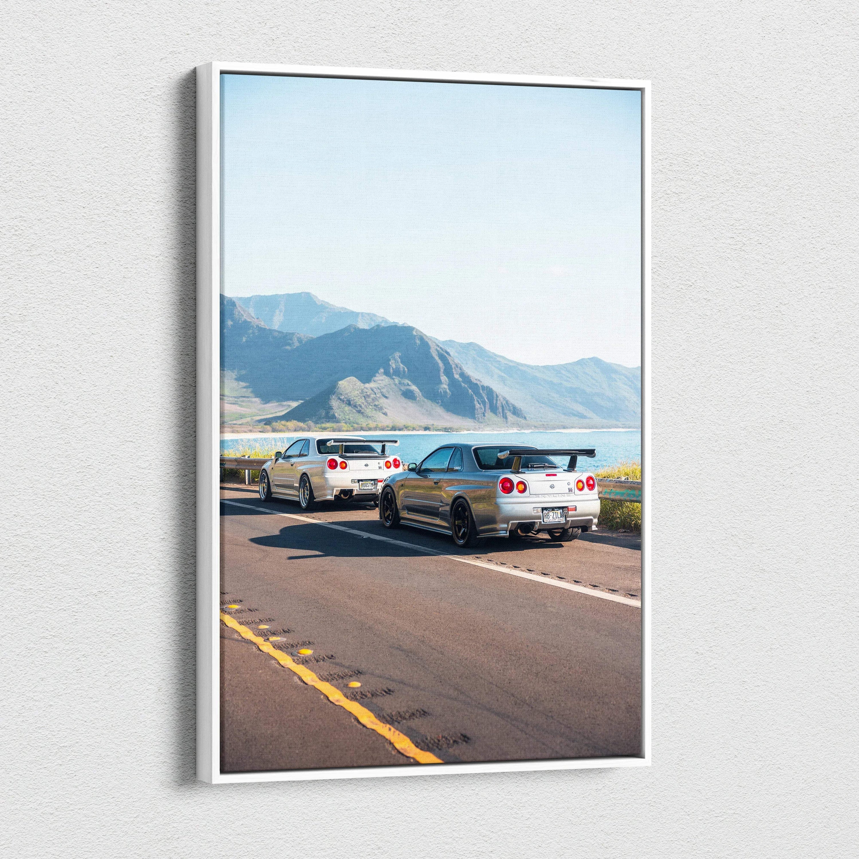 Vertical canvas wall art featuring two Nissan R34 GTR cars on a scenic mountain road.