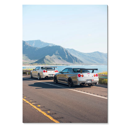 Nissan GT-R R34 Skyline cars driving on mountain road poster wall art with clear blue sky.