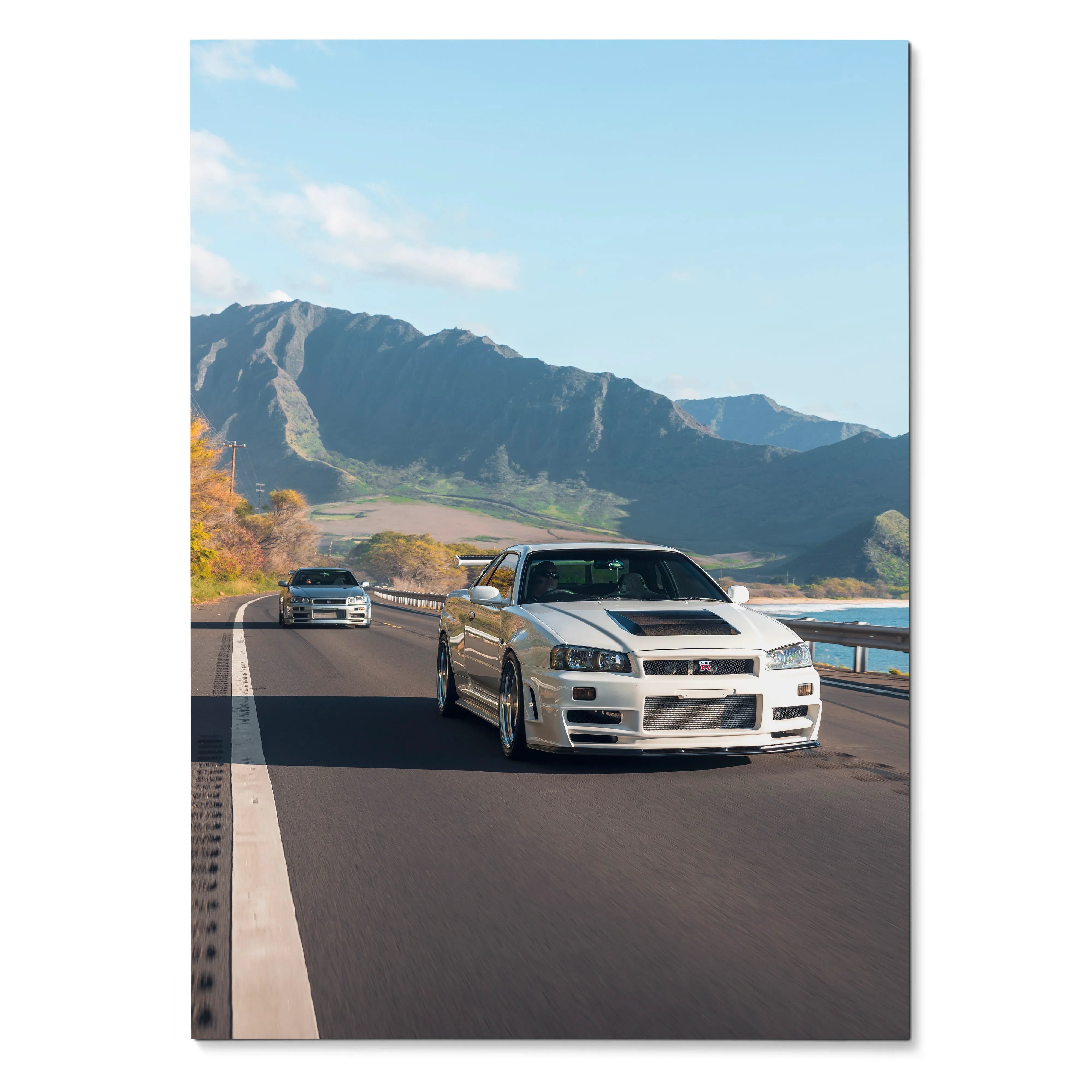 Nissan R34 GT-R driving on coastal road with mountains background poster wall art.