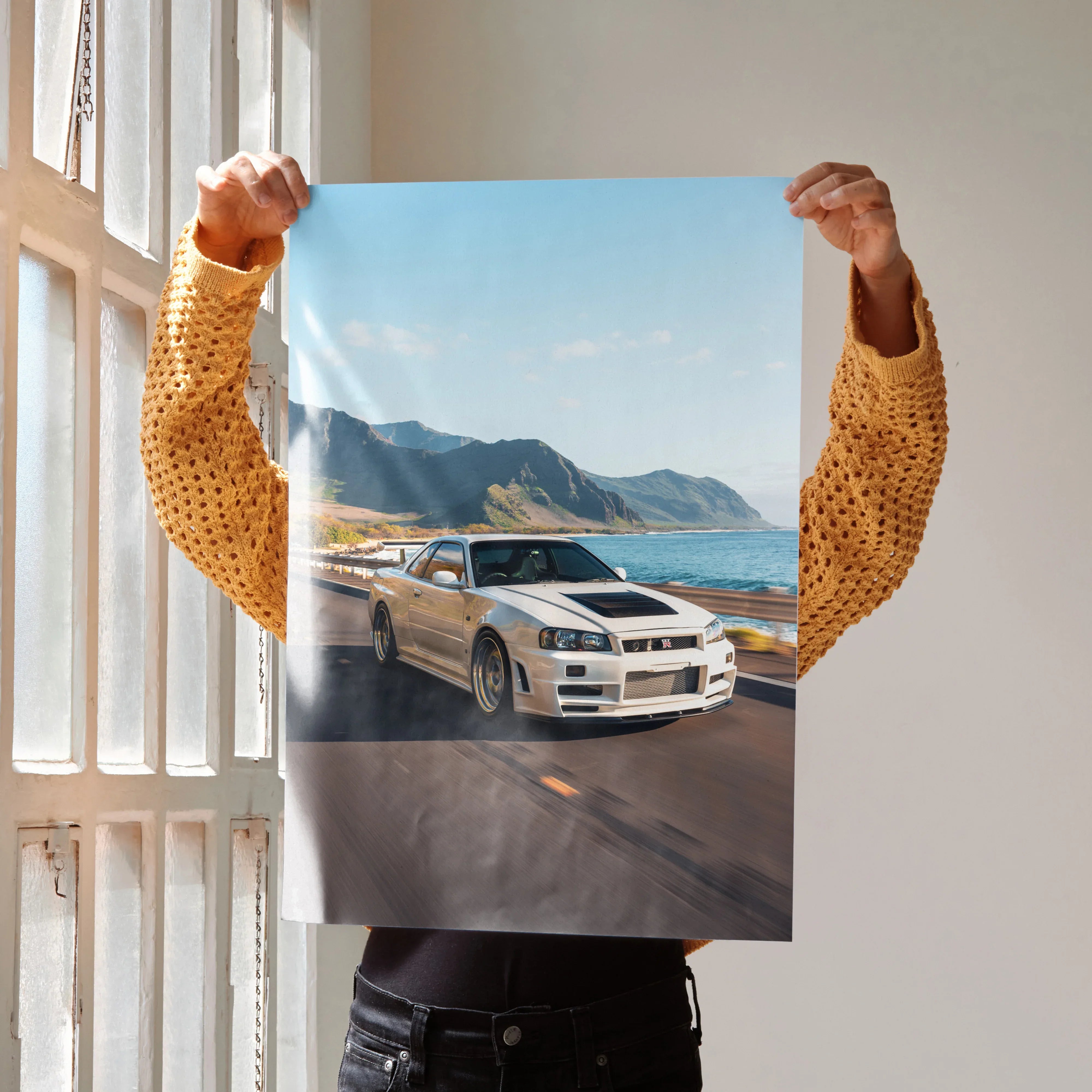 Nissan GT-R R34 Skyline driving on coastal road under blue sky poster wall art.