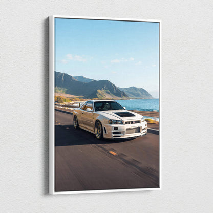 Vertical canvas wall art featuring a white Nissan R34 GTR Skyline on a coastal road with mountains and ocean backdrop.