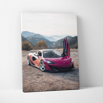Vertical canvas wall art featuring a vibrant red McLaren 600LT with raised doors in a mountainous desert setting.