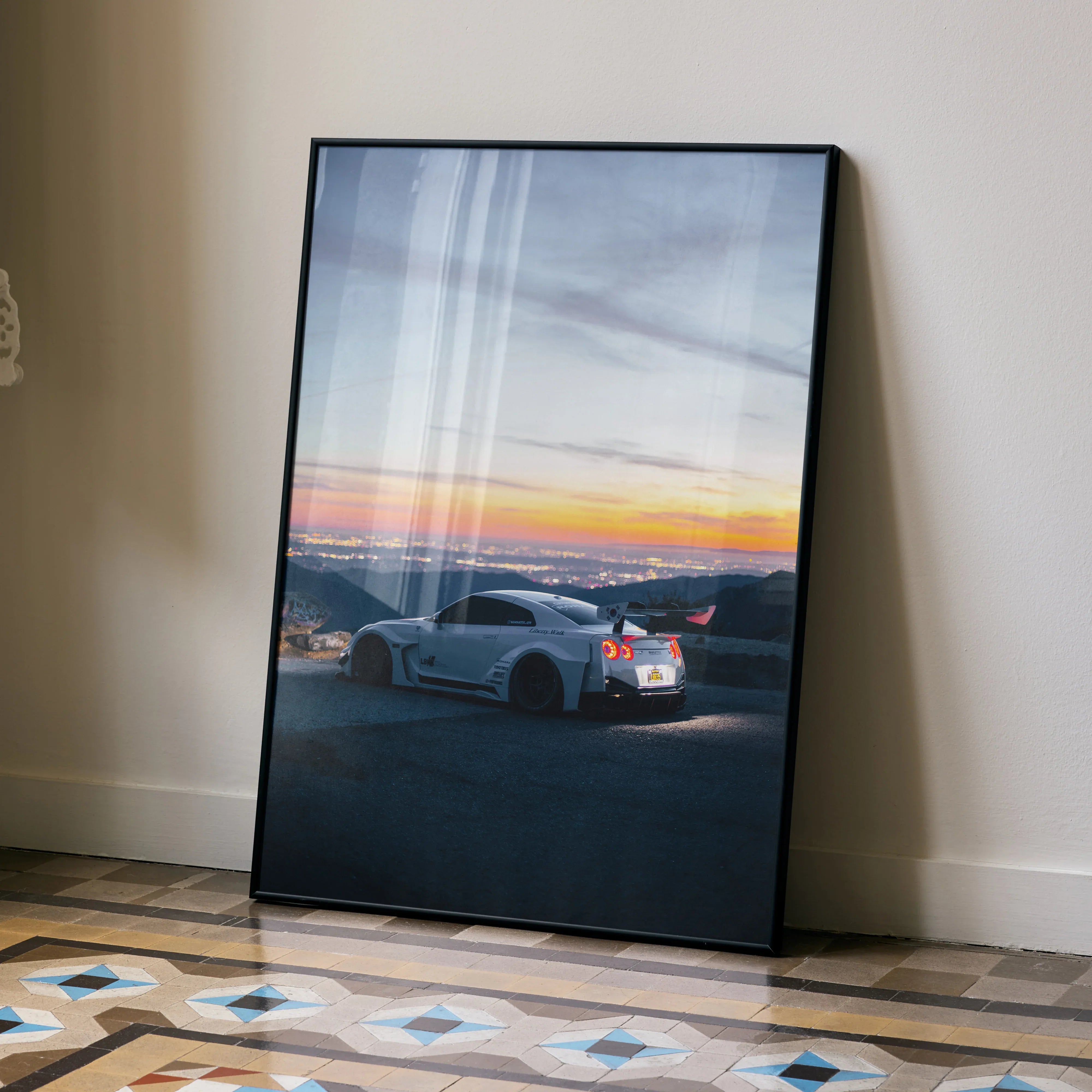 Nissan R35 GT-R sports car at sunset poster wall art in black frame leaning on floor.