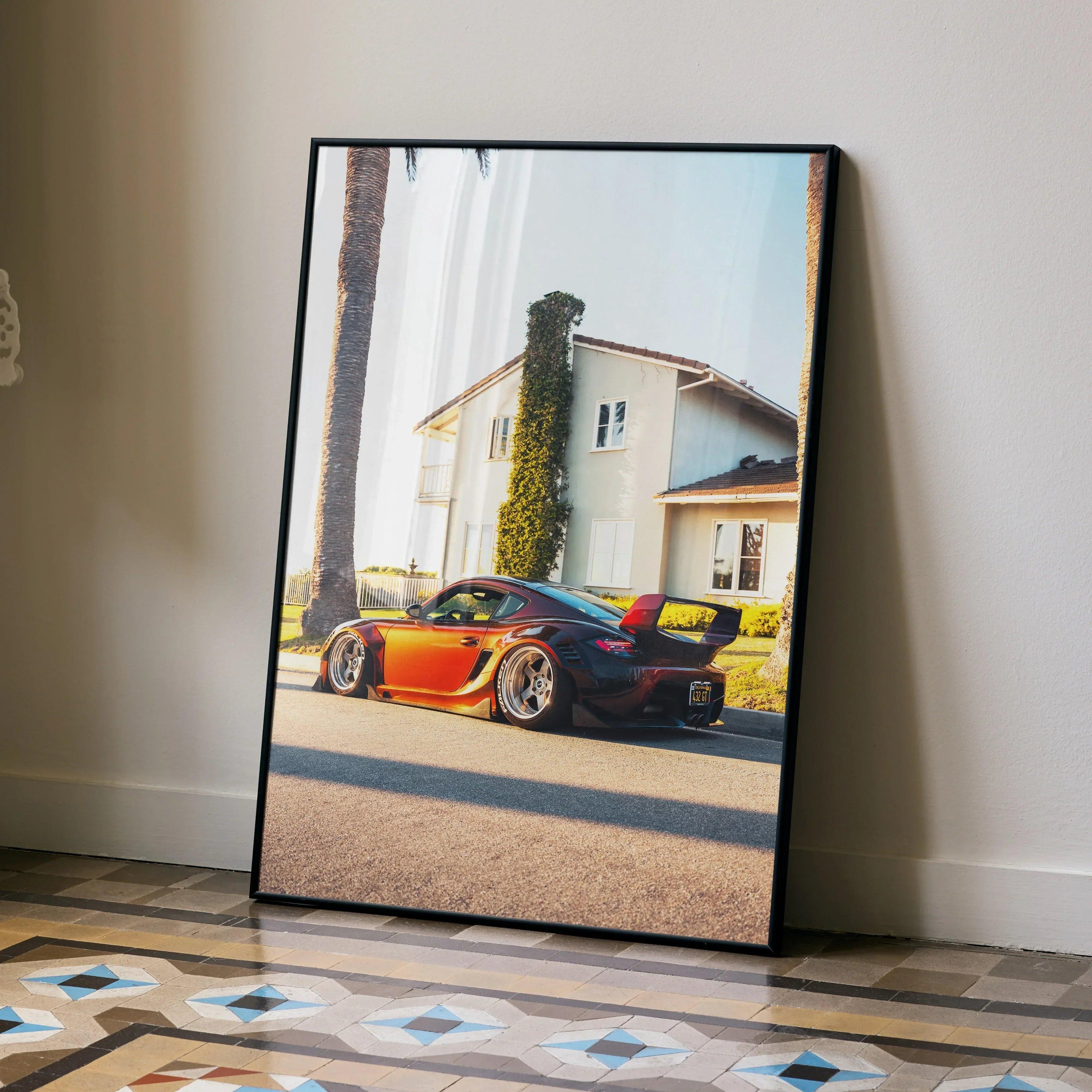 Poster of bright orange Porsche Cayman parked in front of white Mediterranean-style house, premium wall art.