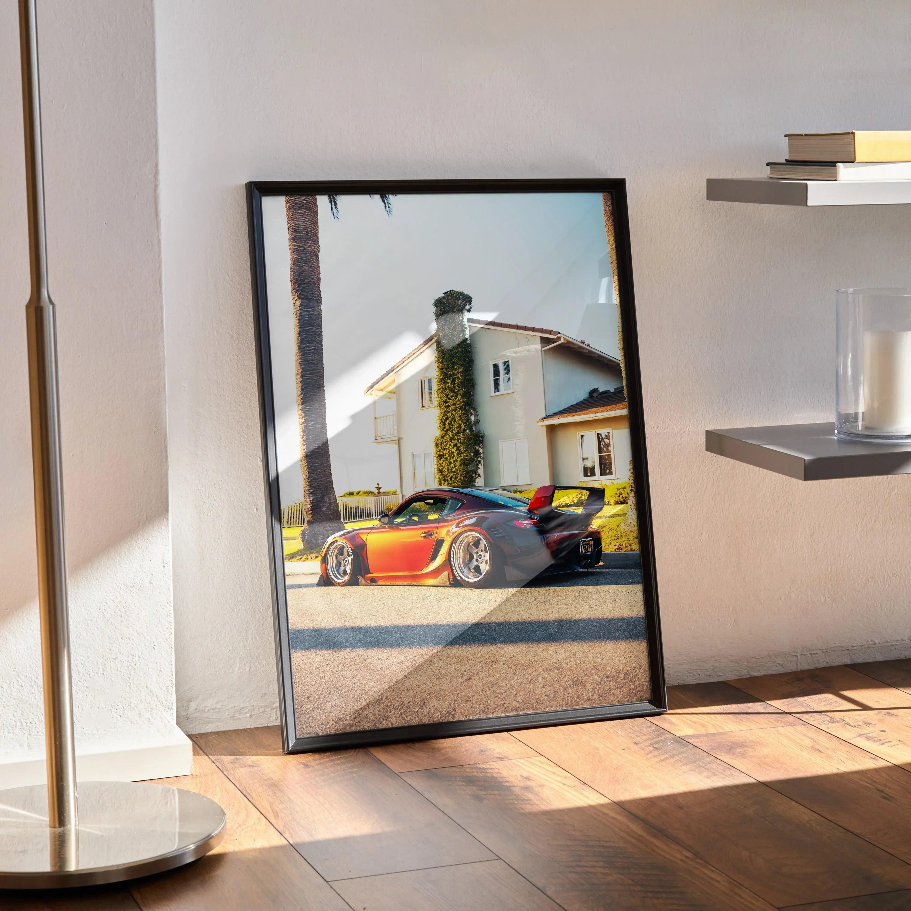 Porsche Cayman poster wall art with vibrant orange sports car in sunny residential setting, framed black.