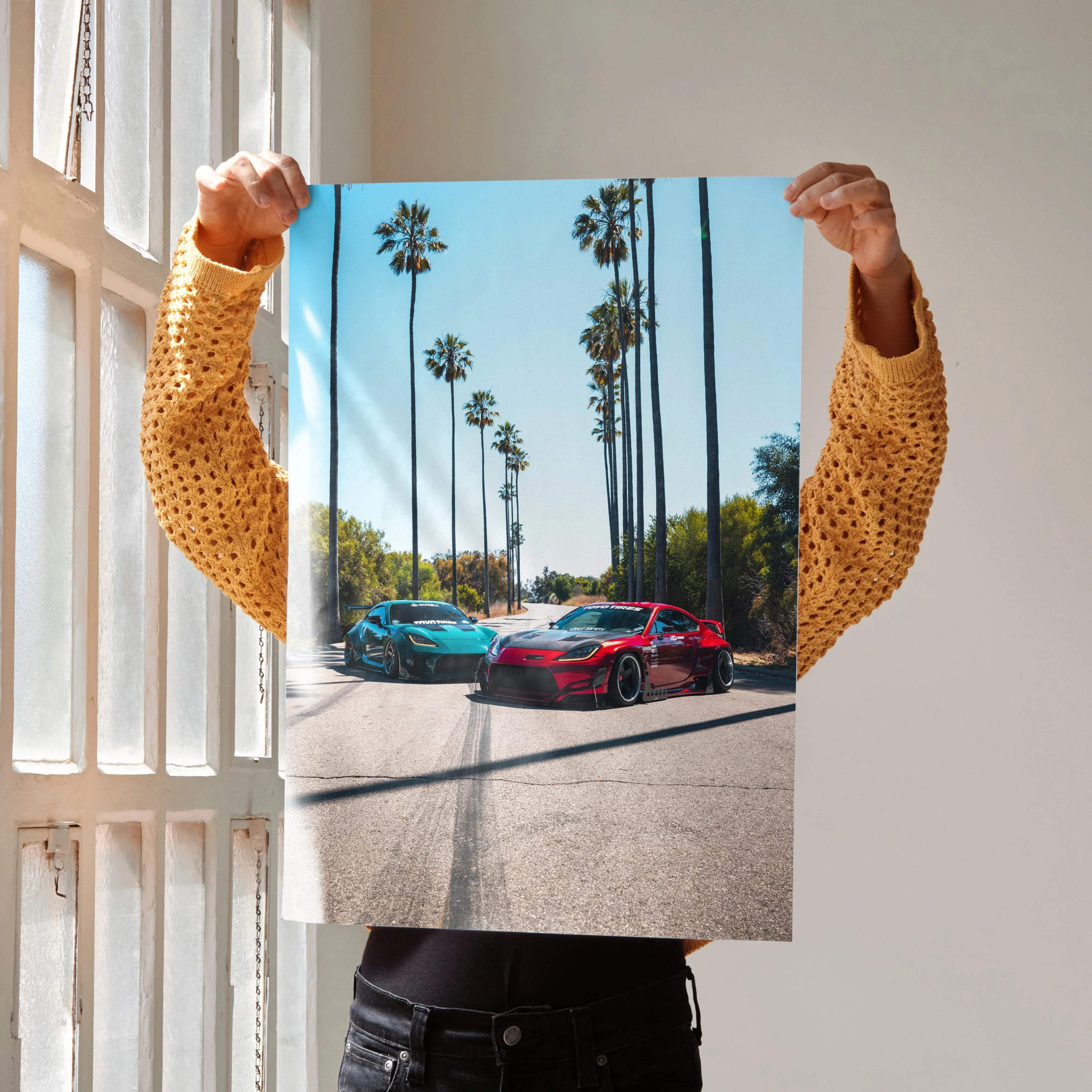 Toyota GR86 wall art poster featuring teal and red modified sports cars speeding down a sunlit palm tree road