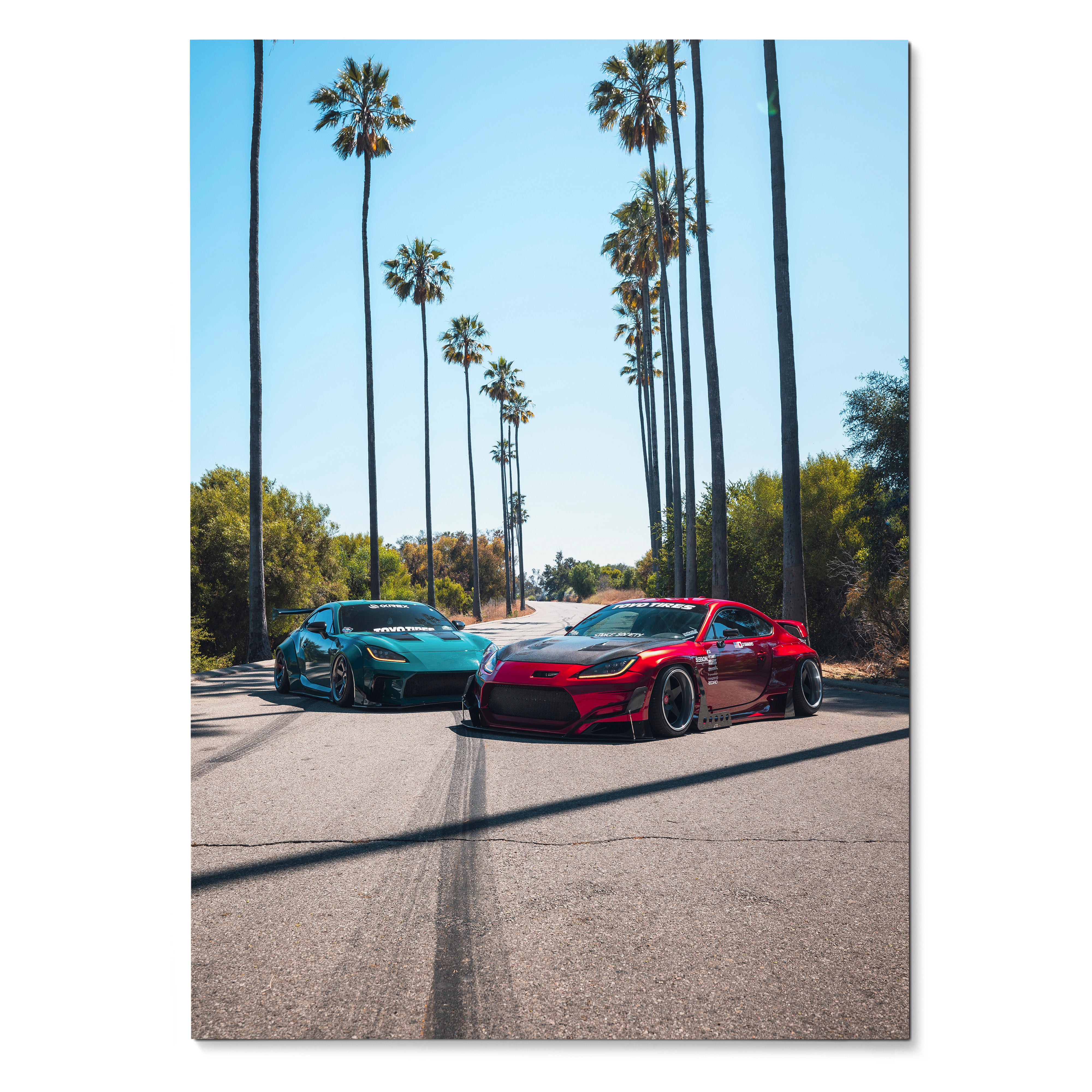 Toyota GR86 and Subaru BRZ sports cars parked on sunlit street with tall palm trees poster wall art.