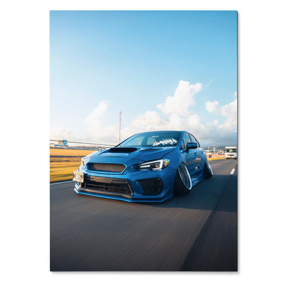 Blue slammed Subaru WRX driving on road poster wall art with clear sky background.