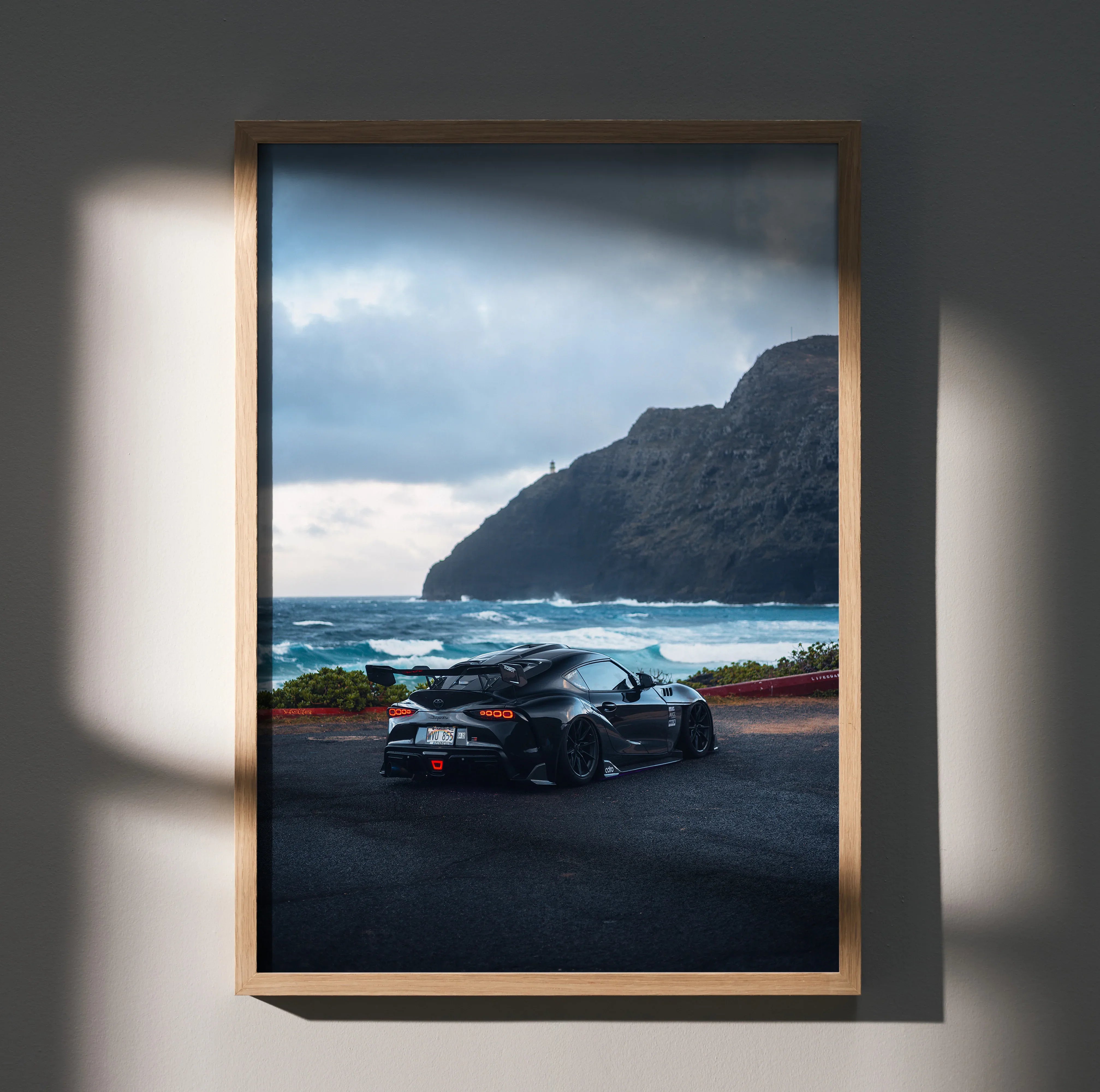 Toyota Supra Mk5 poster wall art featuring black sports car with ocean and mountain backdrop.