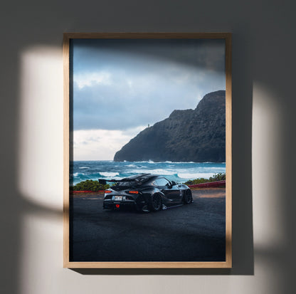 Toyota Supra Mk5 poster wall art featuring black sports car with ocean and mountain backdrop.