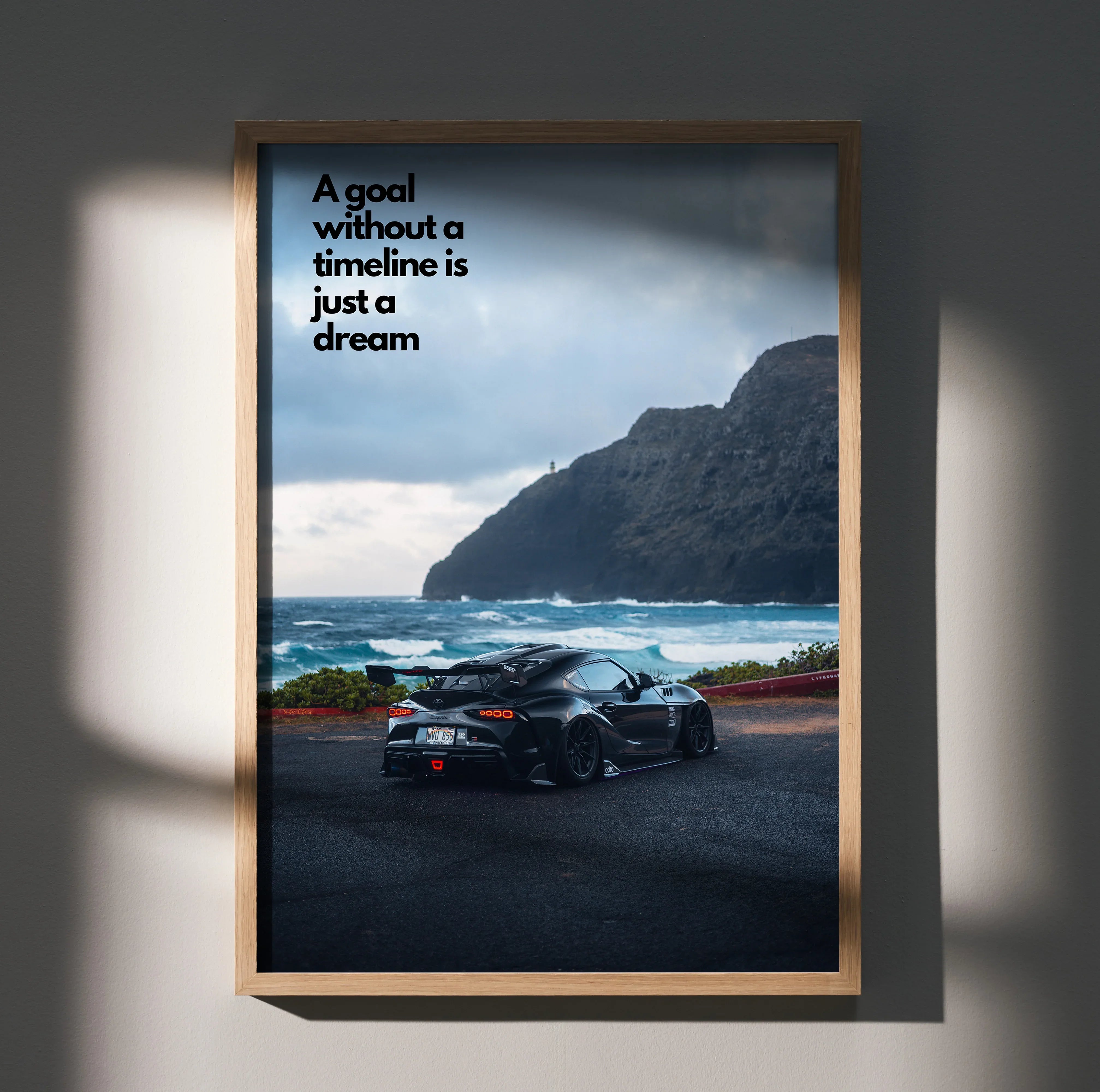 Motivational poster featuring black Toyota Supra Mk5 on coastal road with inspiring text and mountain backdrop wall art.