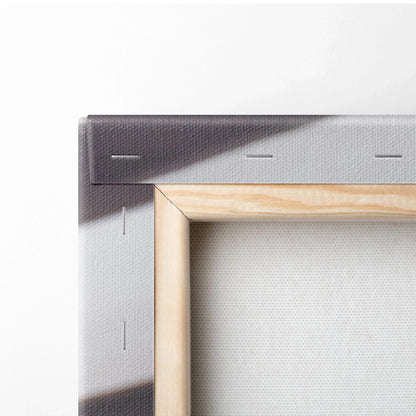 Close-up of wooden frame and stapled edges on white canvas wall art with dark abstract print.