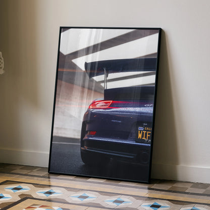 Porsche 911 GT3 RS rear view with spoiler wall art poster in black frame leaning on floor.