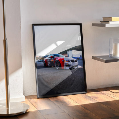 BMW E92 M3 red and silver car poster in black frame leaning against wall, automotive wall art.