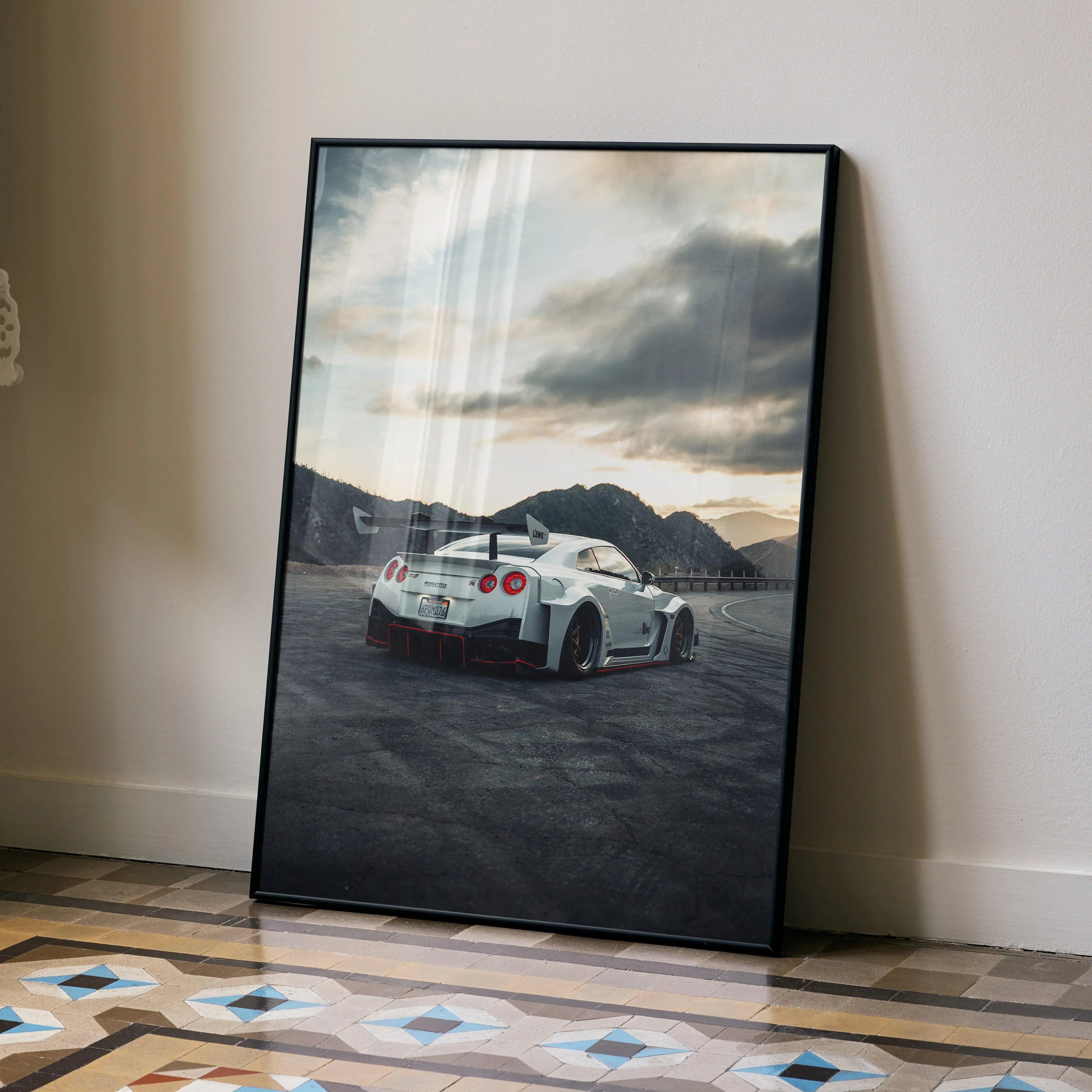 Nissan GTR R35 parked near water at sunset poster wall art with mountains background.