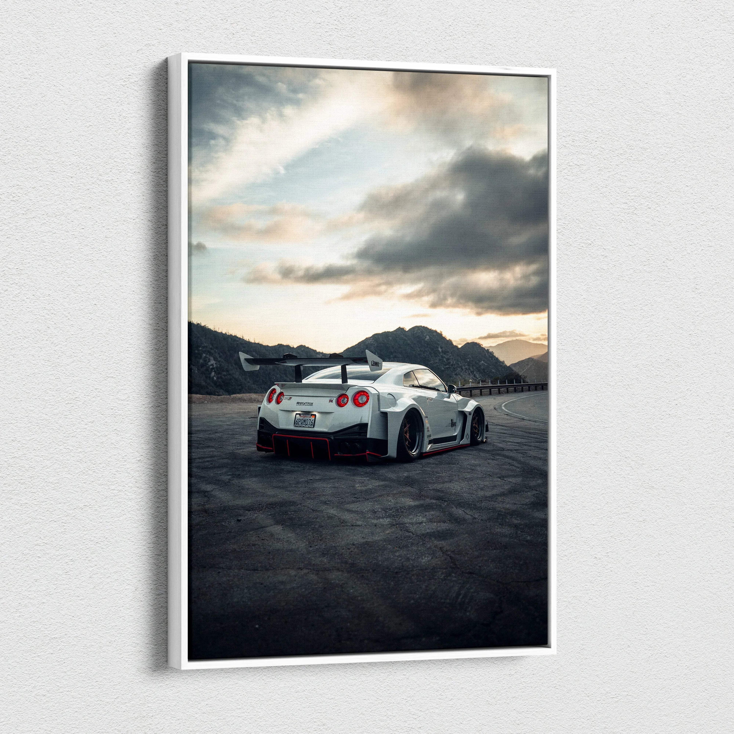 Vertical Nissan R35 GTR canvas art showing a white sports car on asphalt with mountains and cloudy sky background.