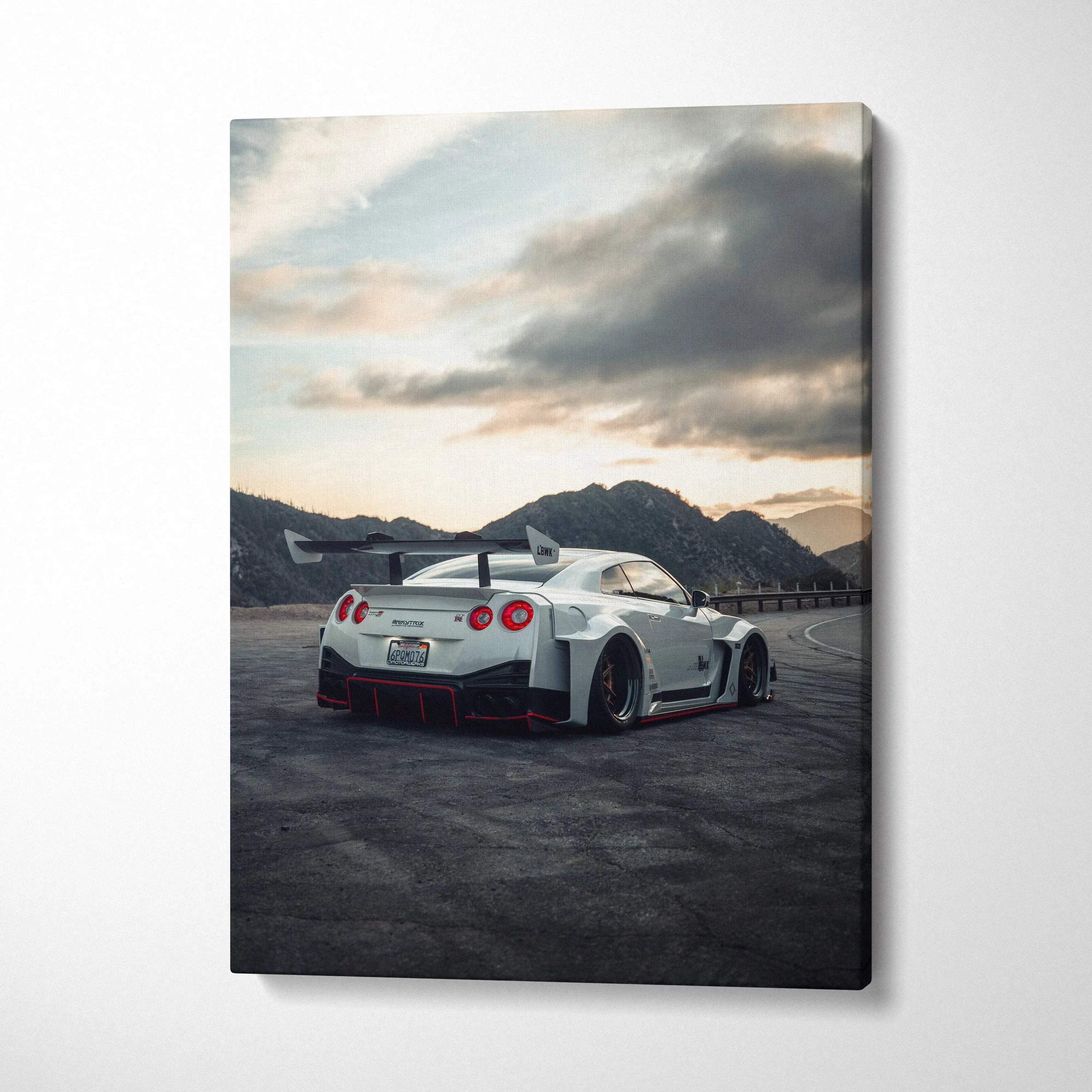 Vertical canvas wall art featuring a white Nissan R35 GTR sports car at sunset with mountainous background.
