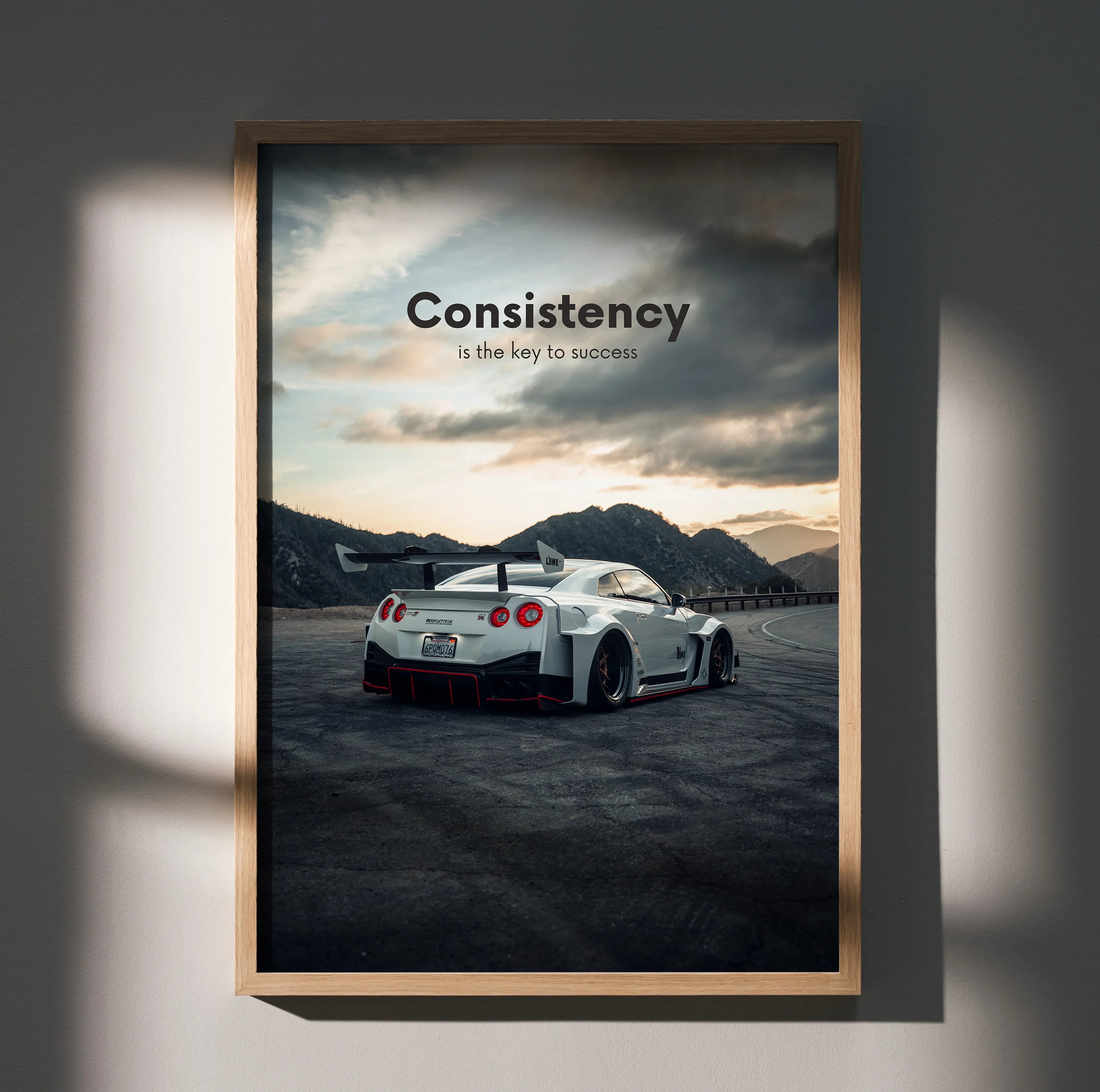 Nissan R35 GT-R poster with "Consistency is the key to success" motivational text, wall art with mountain background.