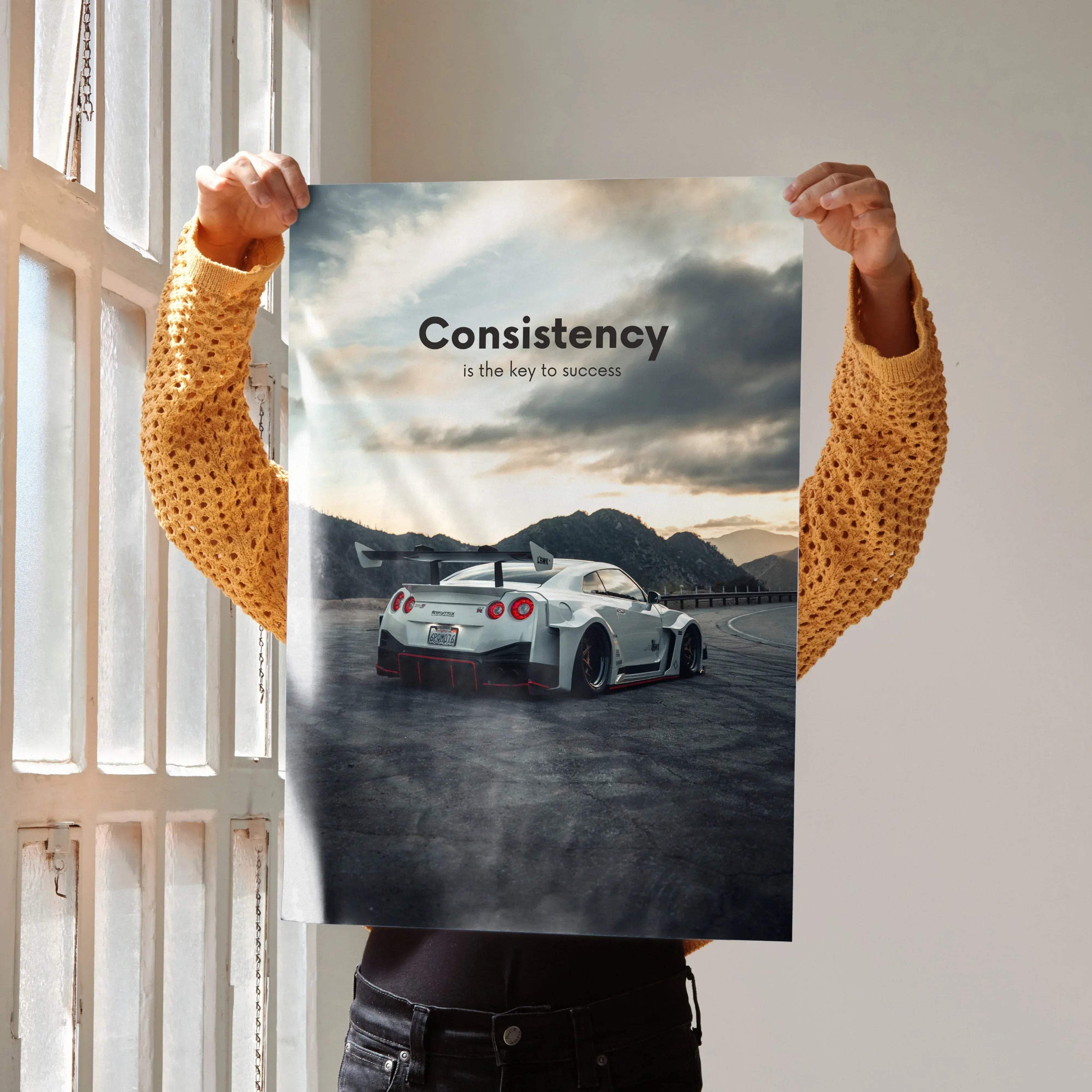 Motivational poster wall art featuring Nissan R35 GT-R with "Consistency is the key" text against a scenic mountain backdrop.