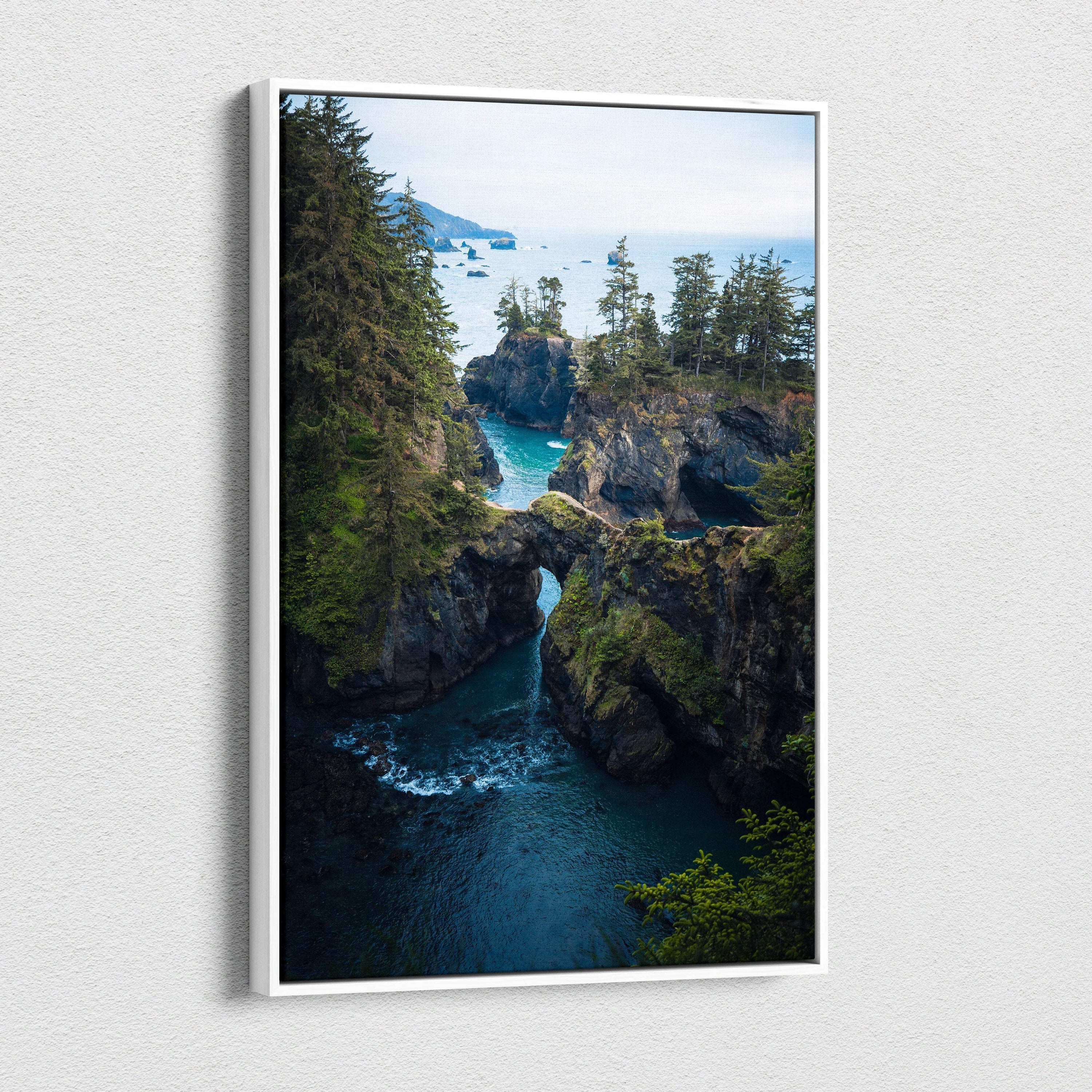 Rugged coastal cliffs with natural rock arch over emerald water and evergreen trees canvas art