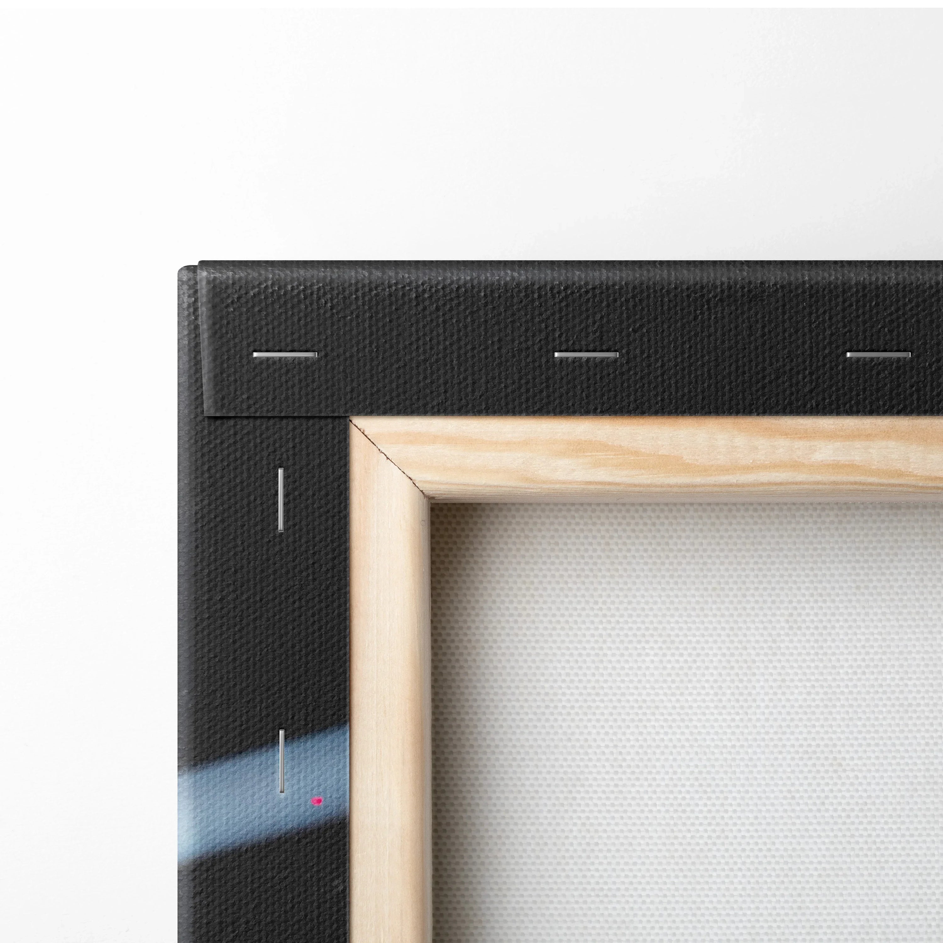 Close-up of wooden frame corner with black wrapped canvas showing texture and staples for wall art canvas print.
