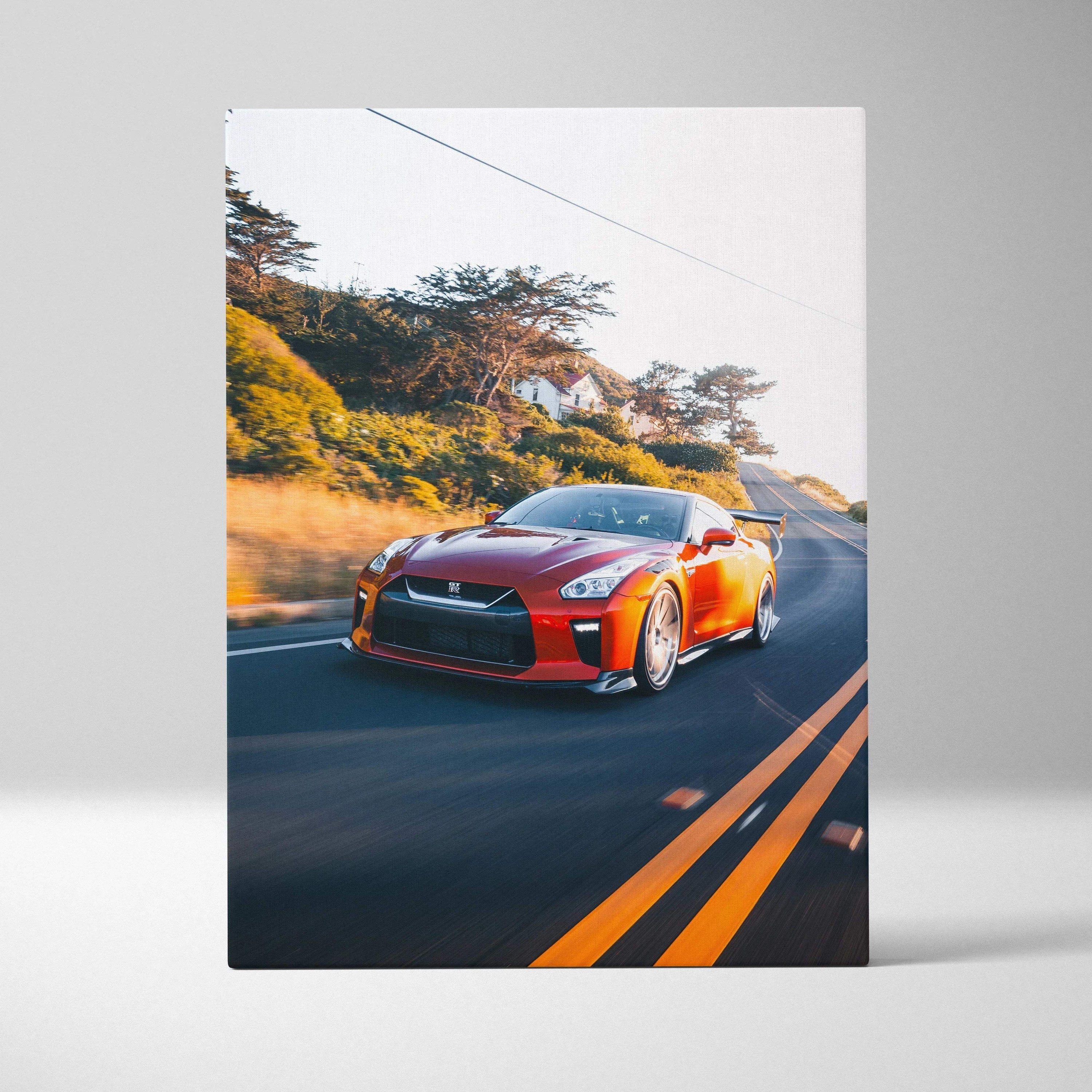 Vertical canvas art of a vibrant orange Nissan R35 GTR speeding on a sunlit road with blurred background.