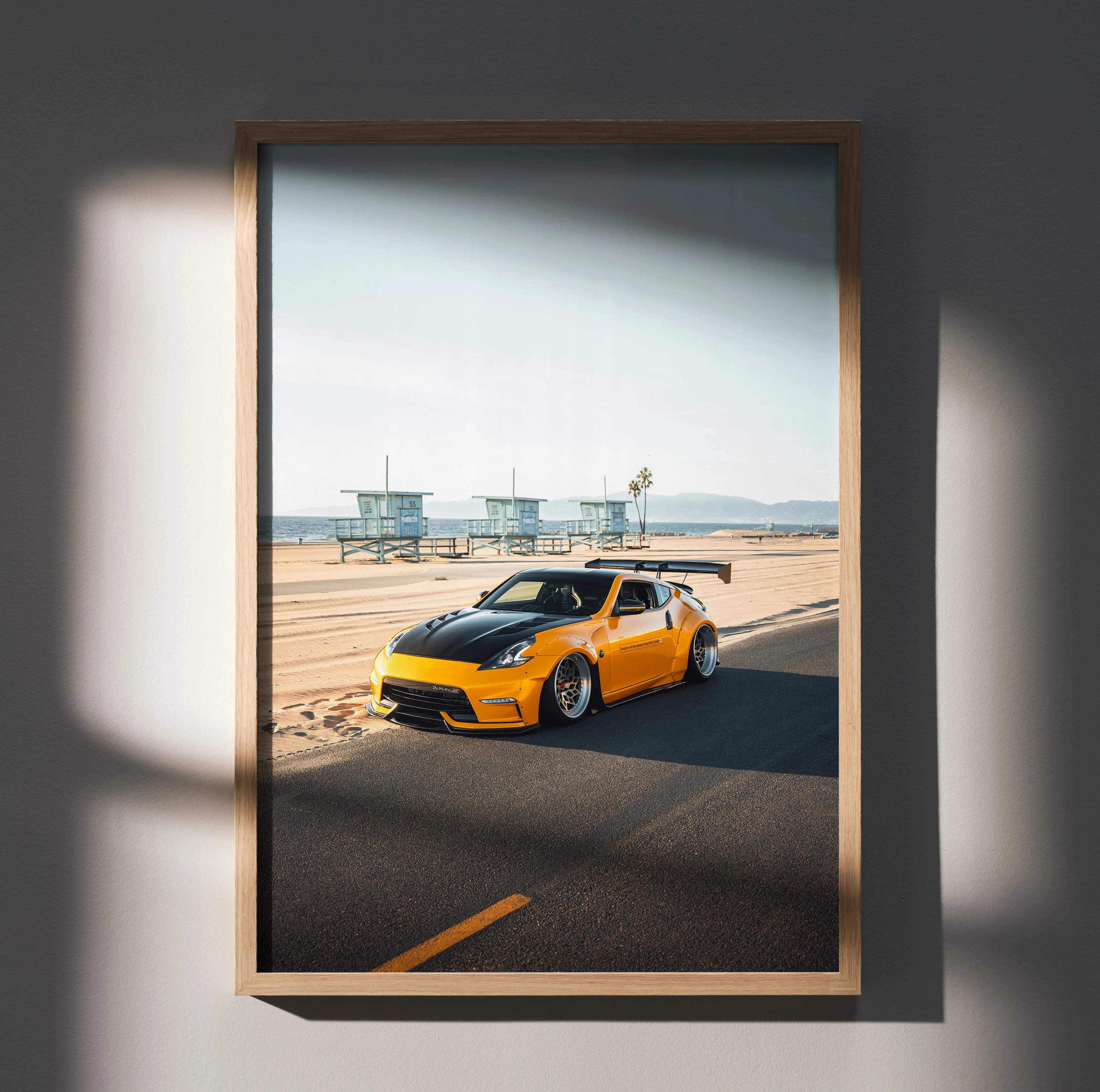 Nissan 370z in vibrant yellow on coastal road poster wall art in wooden frame.