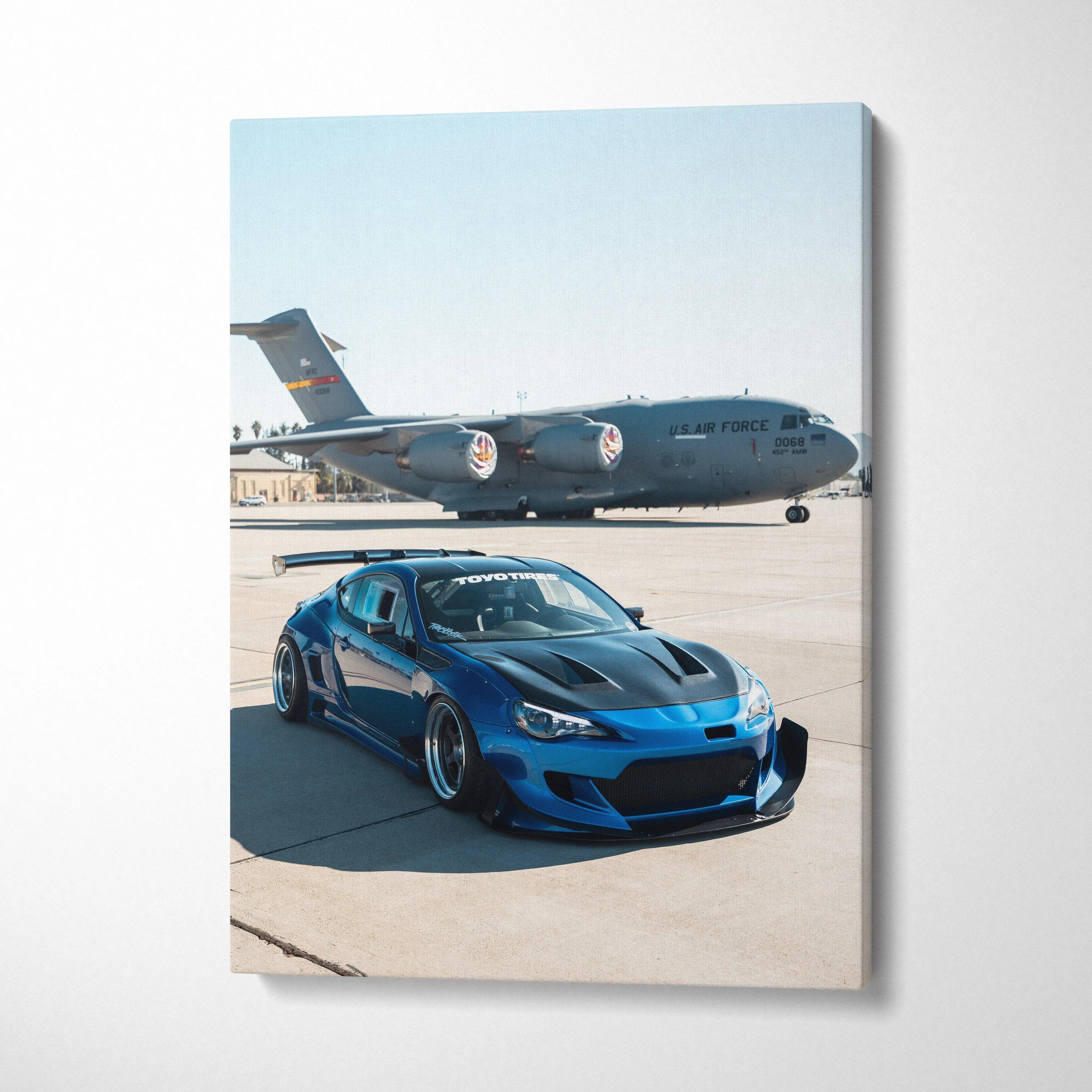 Blue Toyota FRS parked on runway with military cargo plane in background vertical canvas wall art.