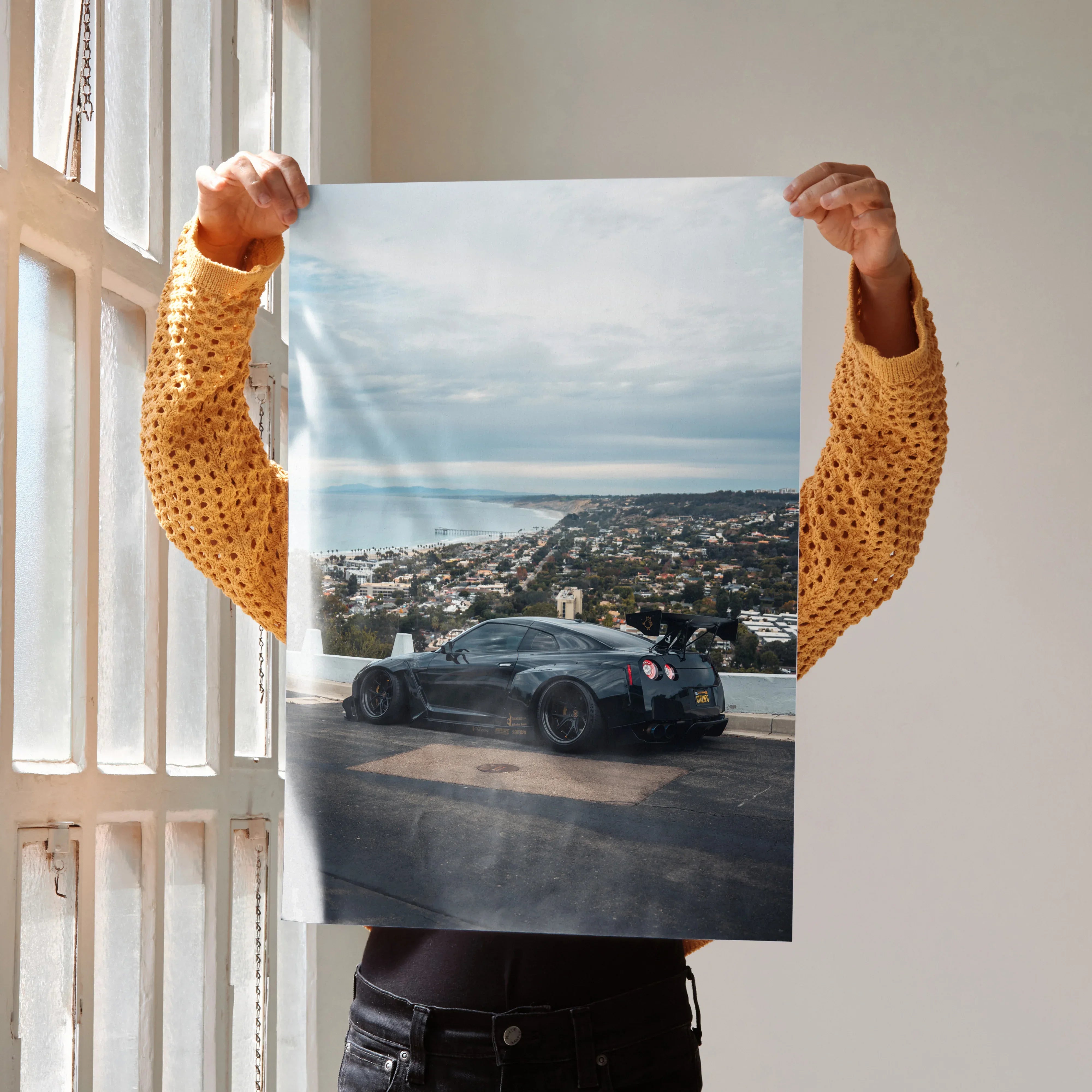 Nissan GTR R35 parked by coastal road poster wall art with city skyline background.