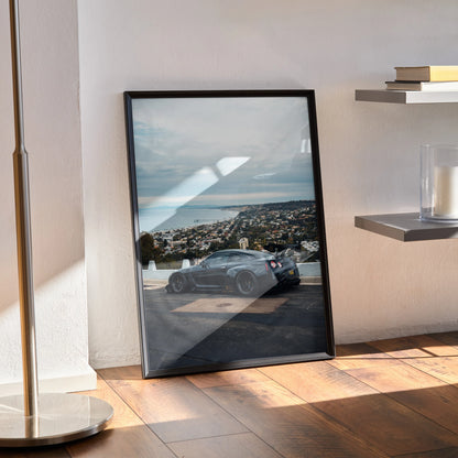 Sleek Nissan GTR R35 poster wall art with cityscape background in black frame on wooden floor.