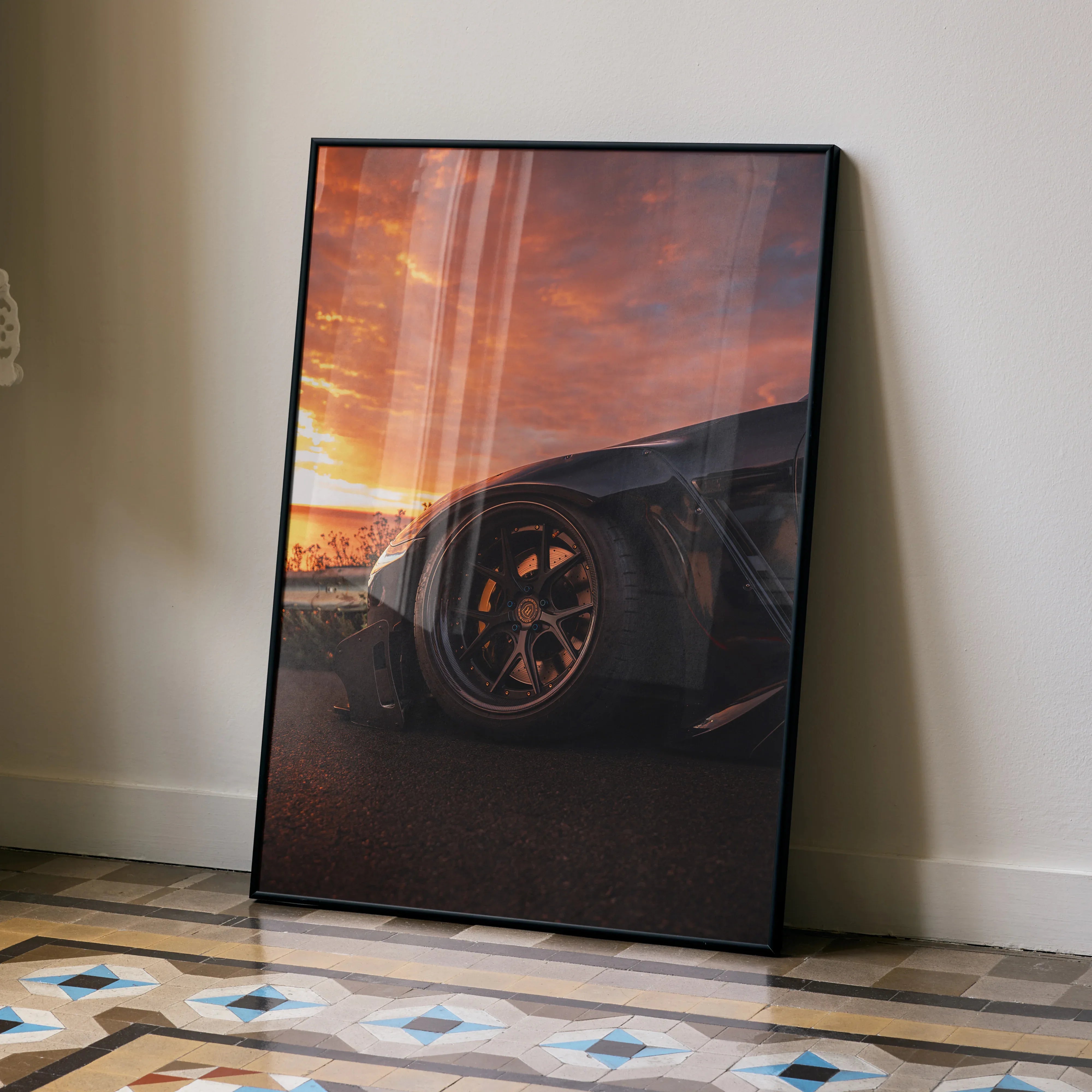 Sleek Nissan GTR R35 poster with dramatic sunset wall art in black frame resting on floor.