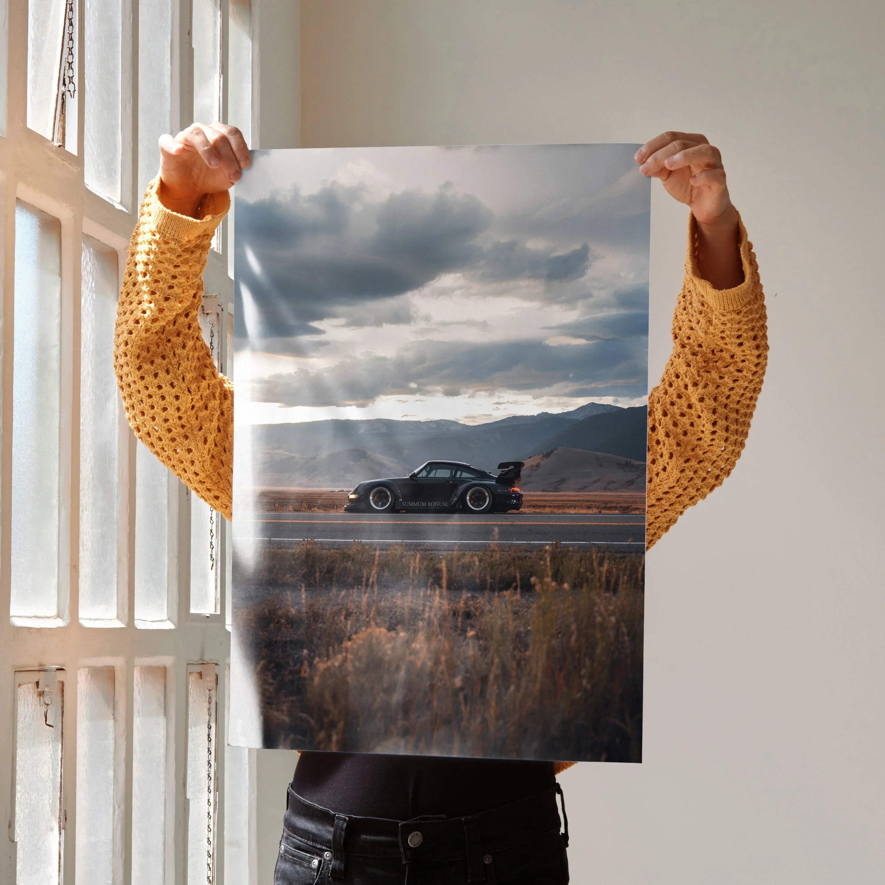 RWB Porsche 911 poster featuring a black sports car on a scenic road at sunset, wall art with dramatic clouds.