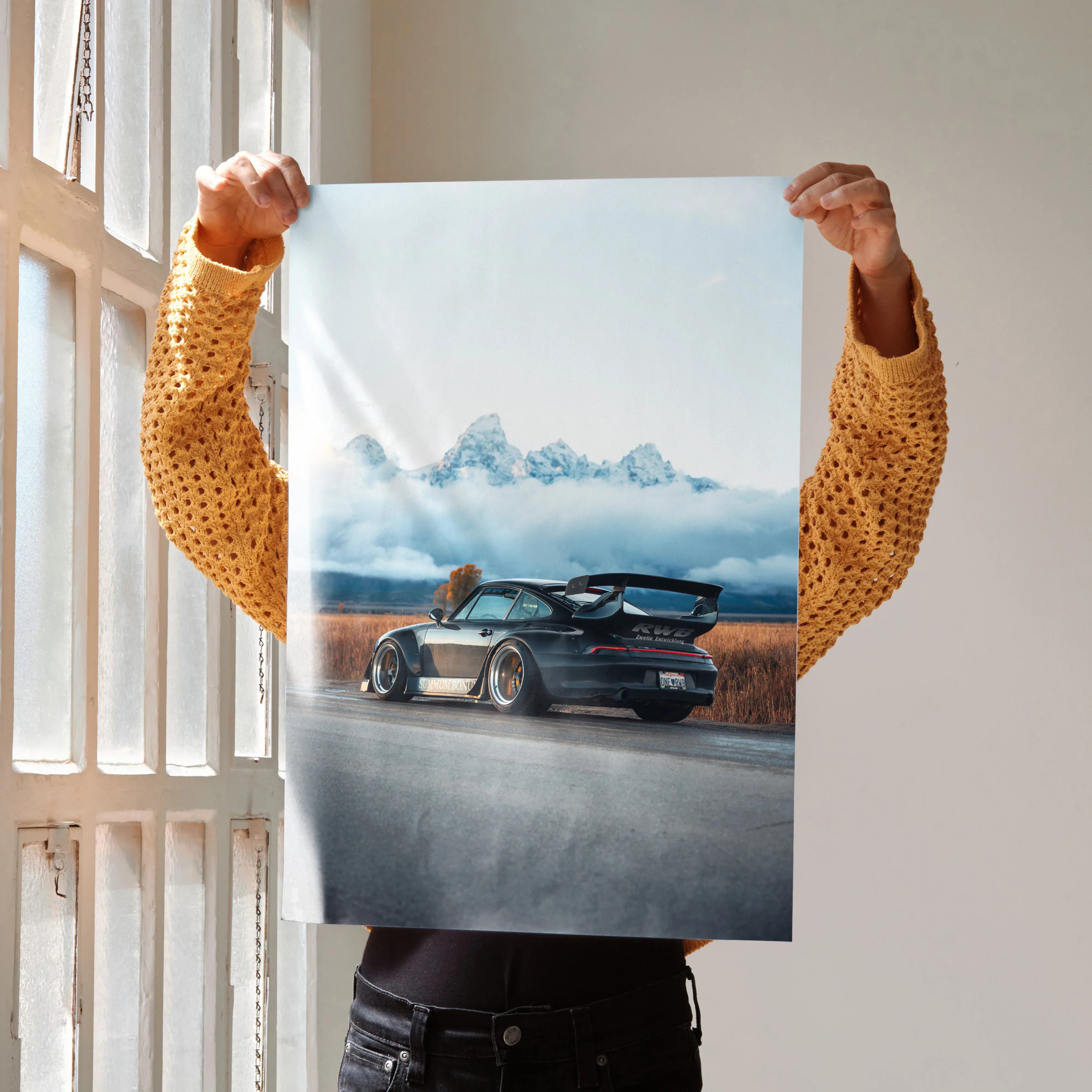 Poster of a black RWB Porsche 911 on a road with mountains in the background, wall art perfect for car enthusiasts.
