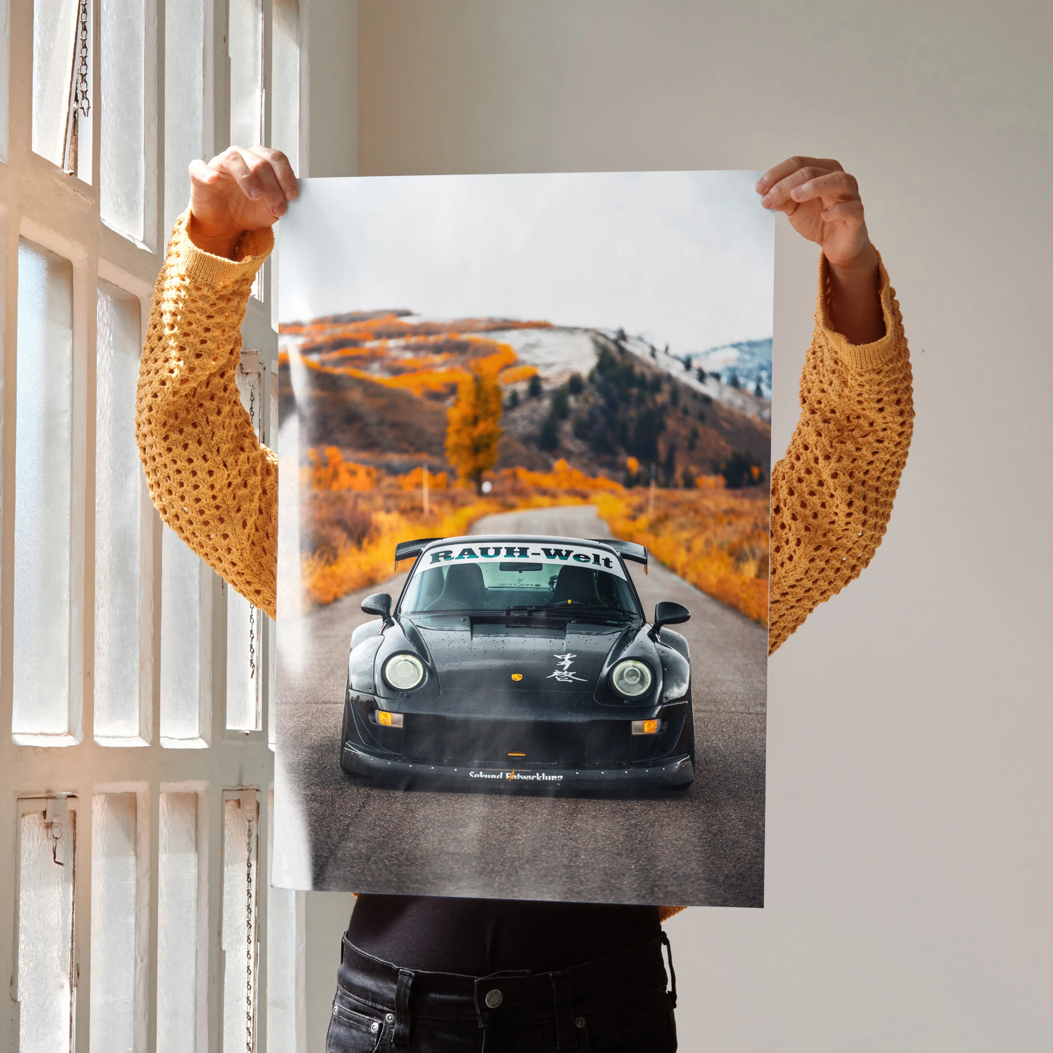 Poster of black RWB Porsche 911 car driving on mountain road with autumn foliage wall art.