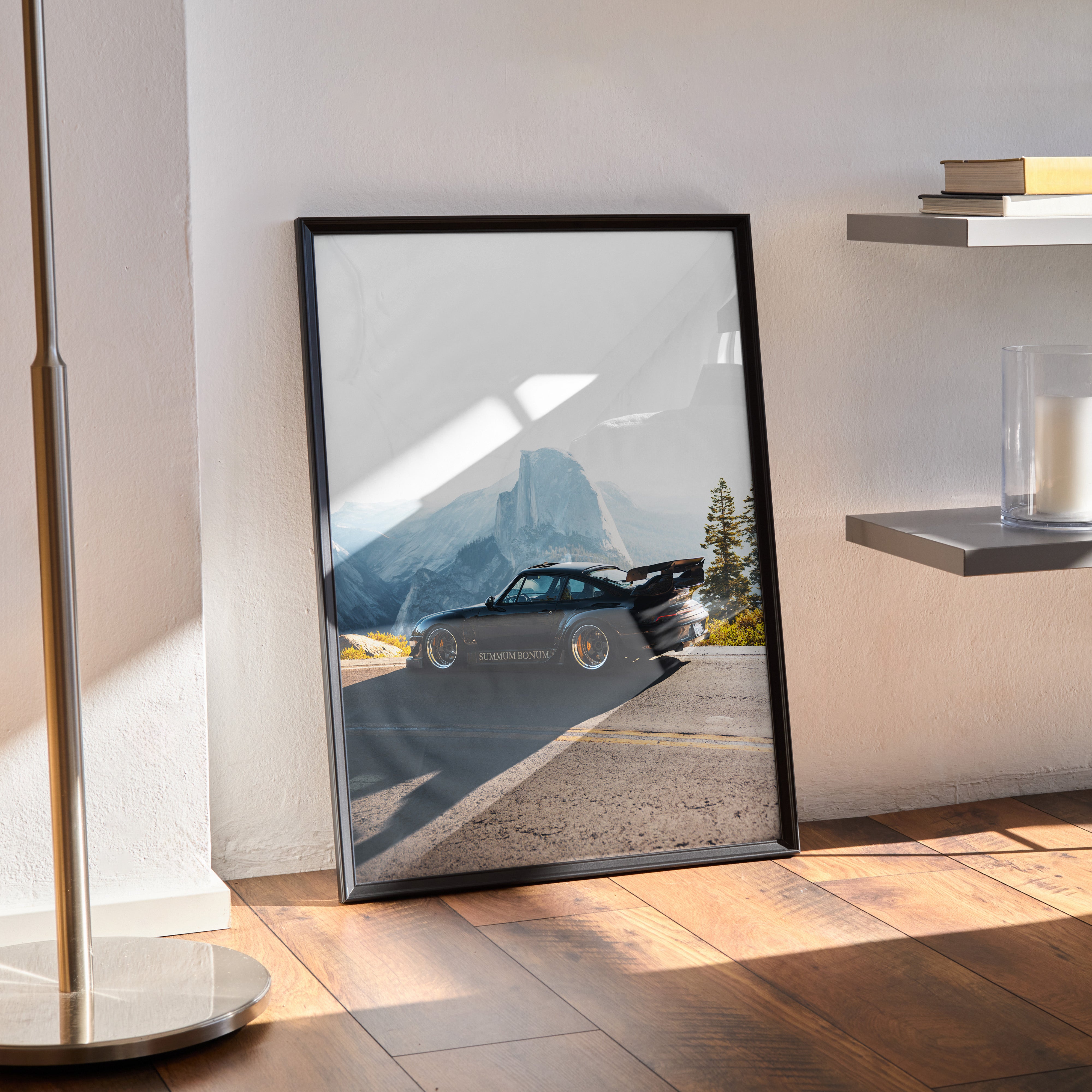 Black-framed RWB Porsche 911 poster leaning against white wall, modern automotive wall art with mountain background.