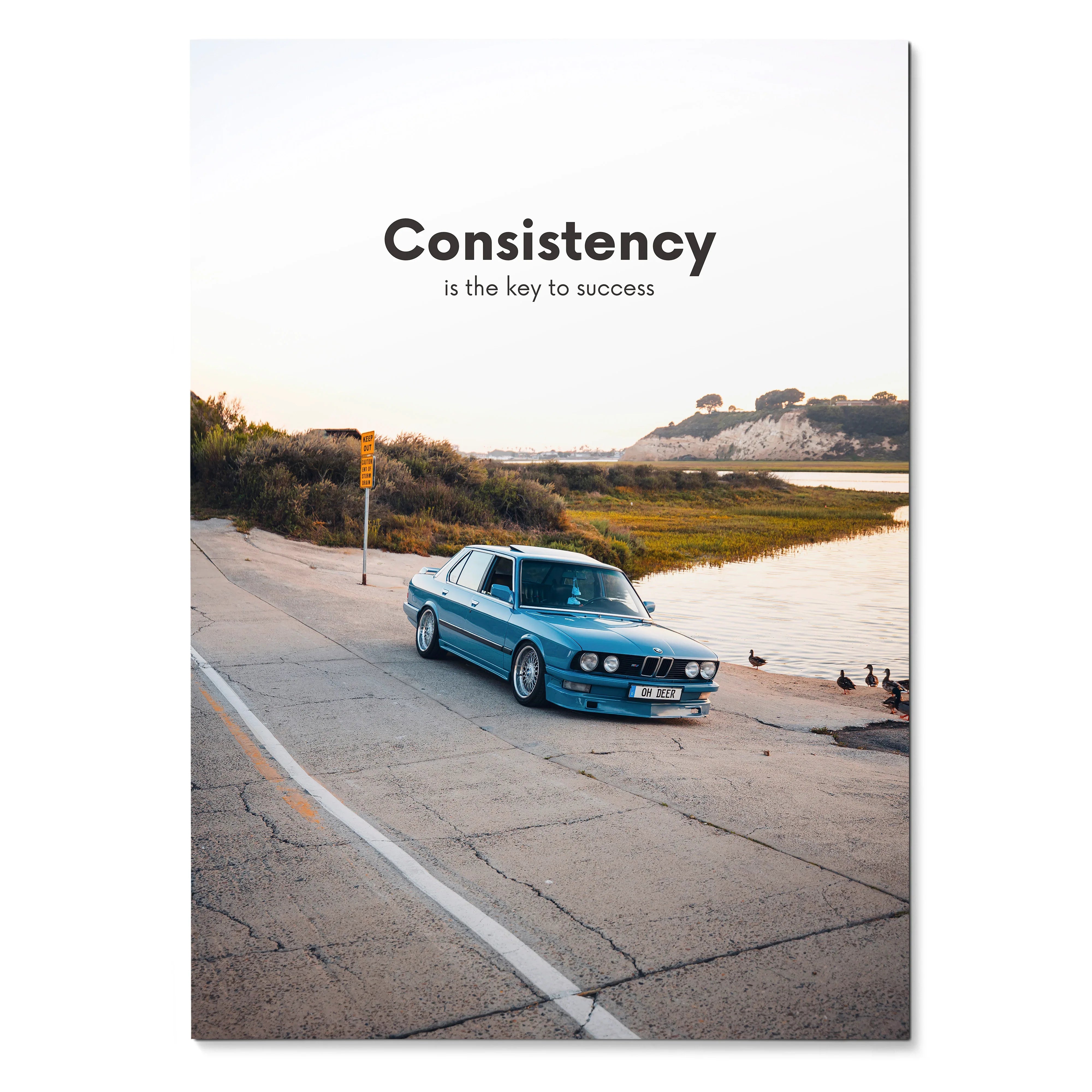BMW E30 poster with blue car on coastal road and motivational quote wall art.