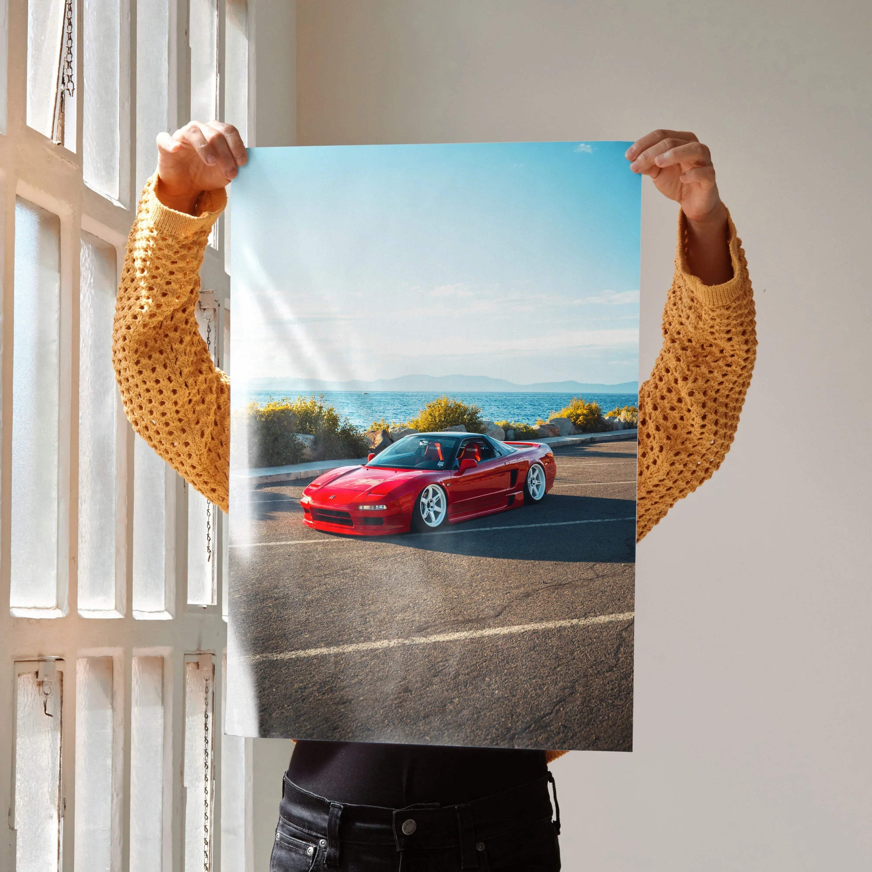 Red Acura NSX sports car on coastal road poster wall art with clear blue sky background.