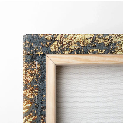 Close-up of canvas wall art corner with black and gold textured frame and natural wood inner trim.