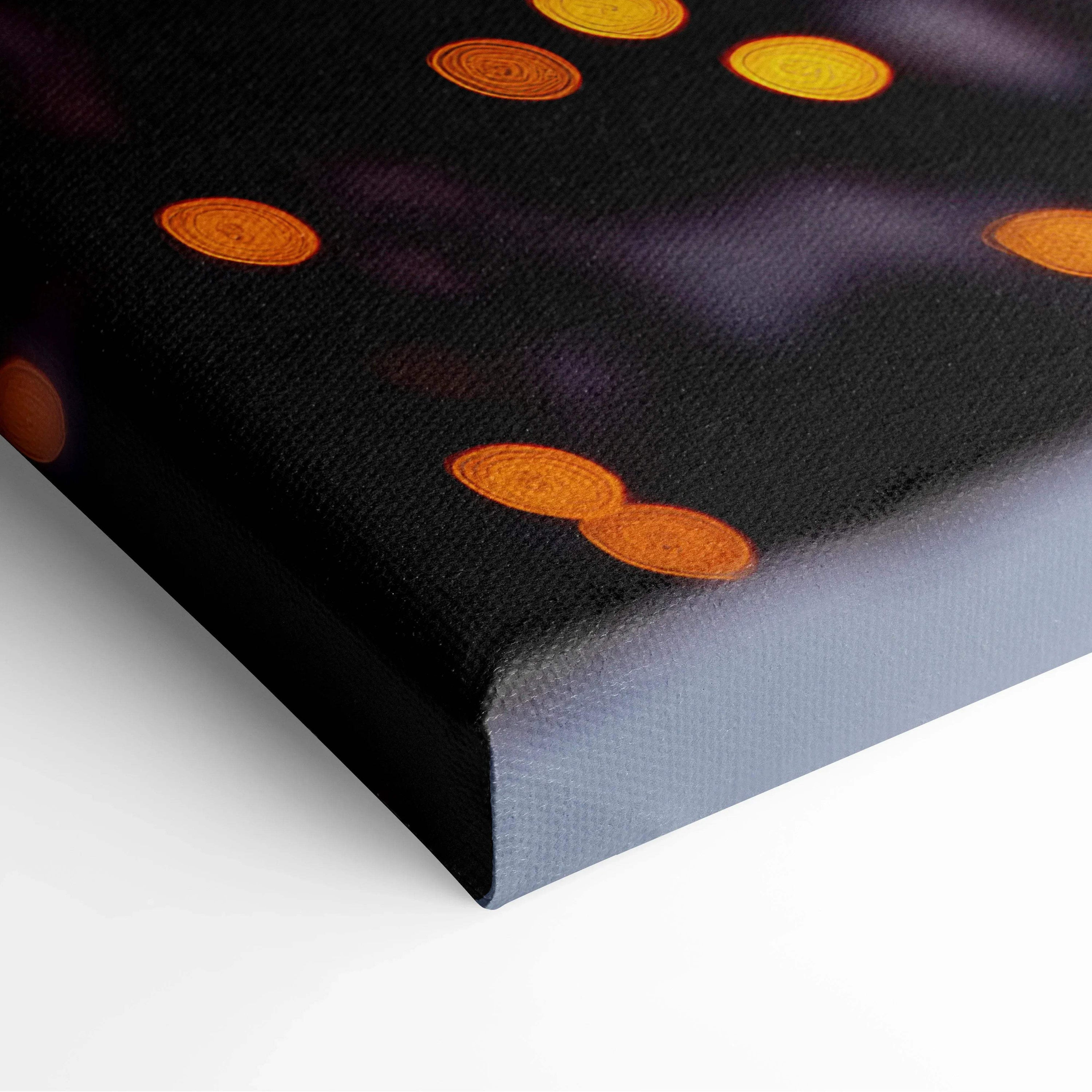 Close-up of black canvas wall art with glowing orange circular light details and textured surface.