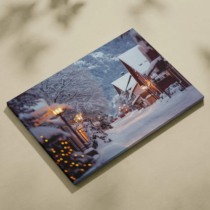 Canvas wall art depicting a snowy mountain town at dusk with lit houses and snow-covered trees.